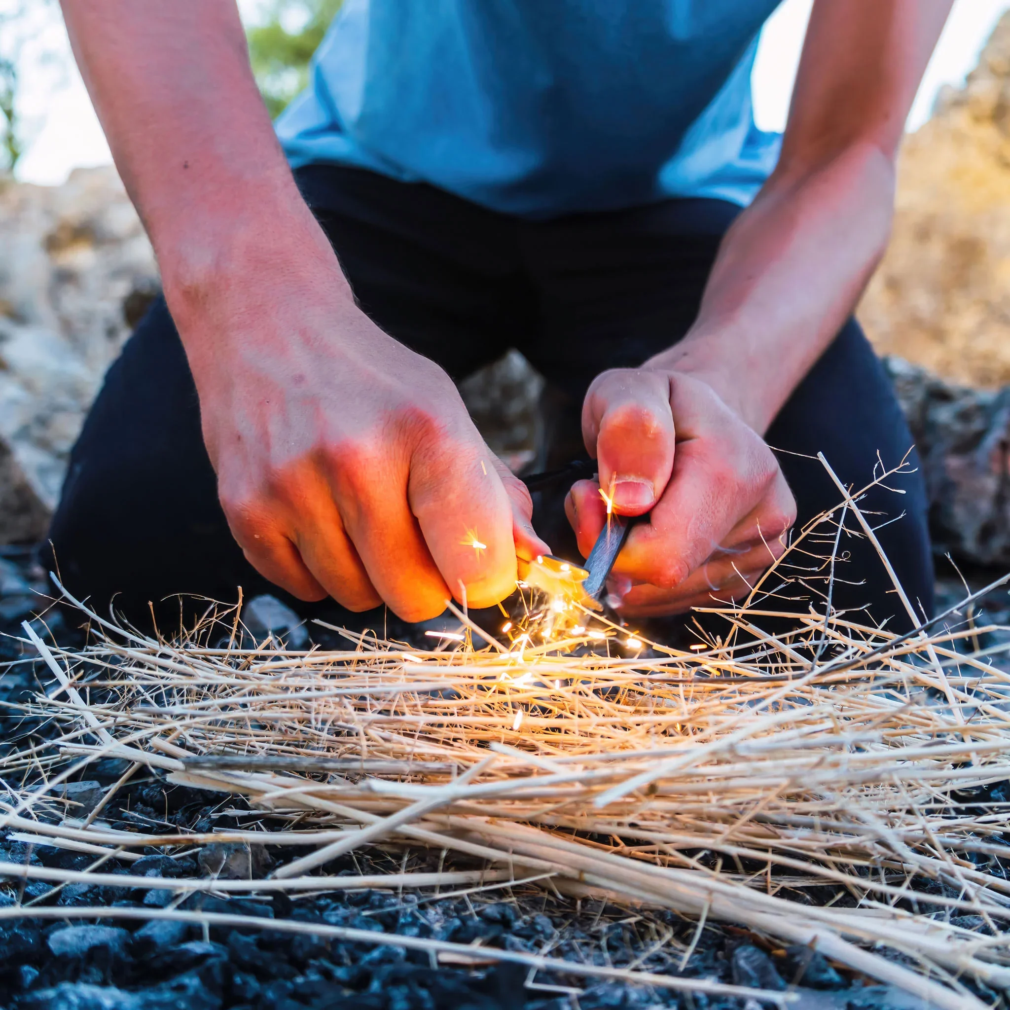Person using a metal file on dry sticks to create sparks.
