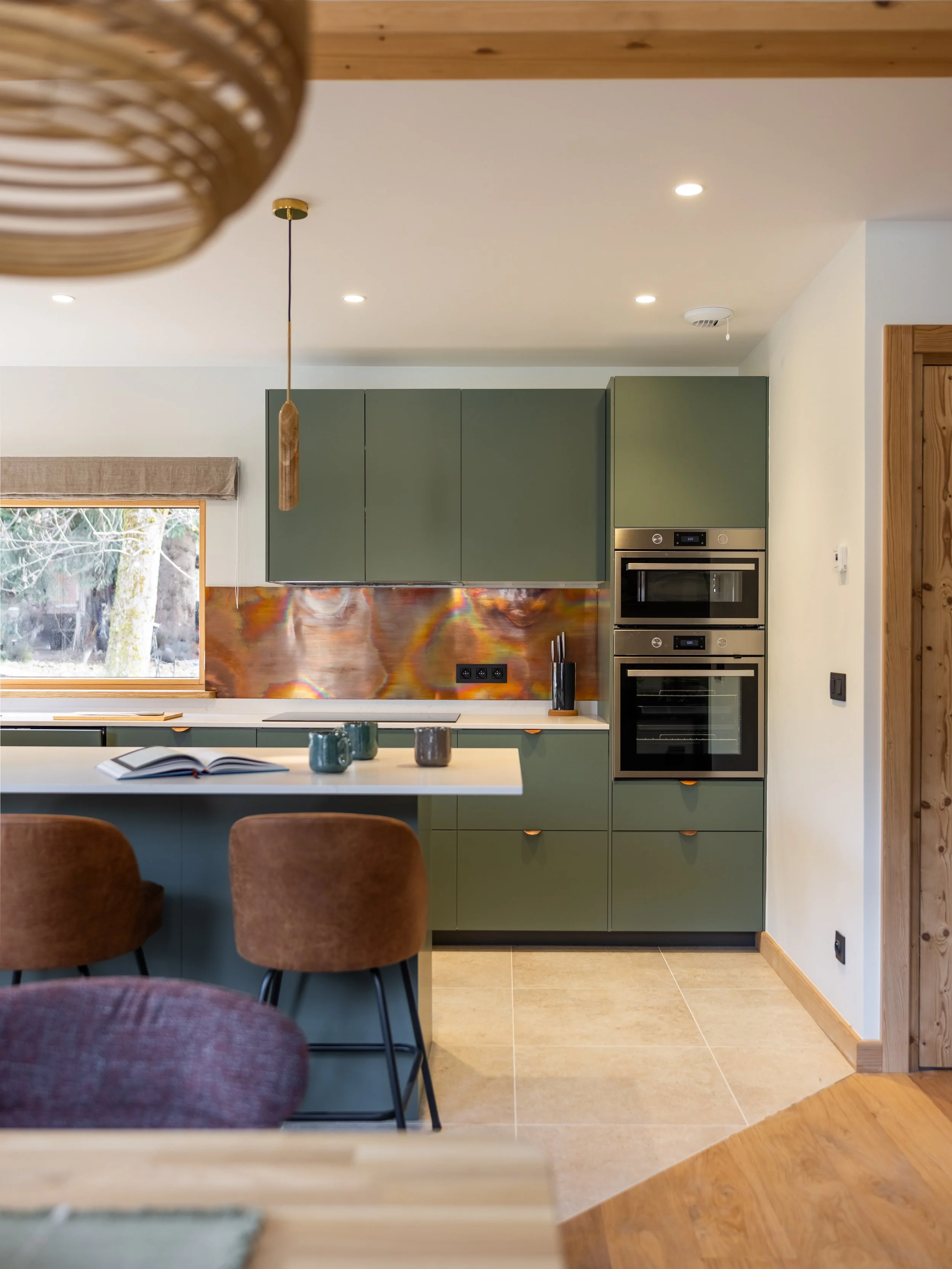 Modern kitchen by Ikea with a copper splashback, marble worktop and travertin floor creating a practical alpine style space. 