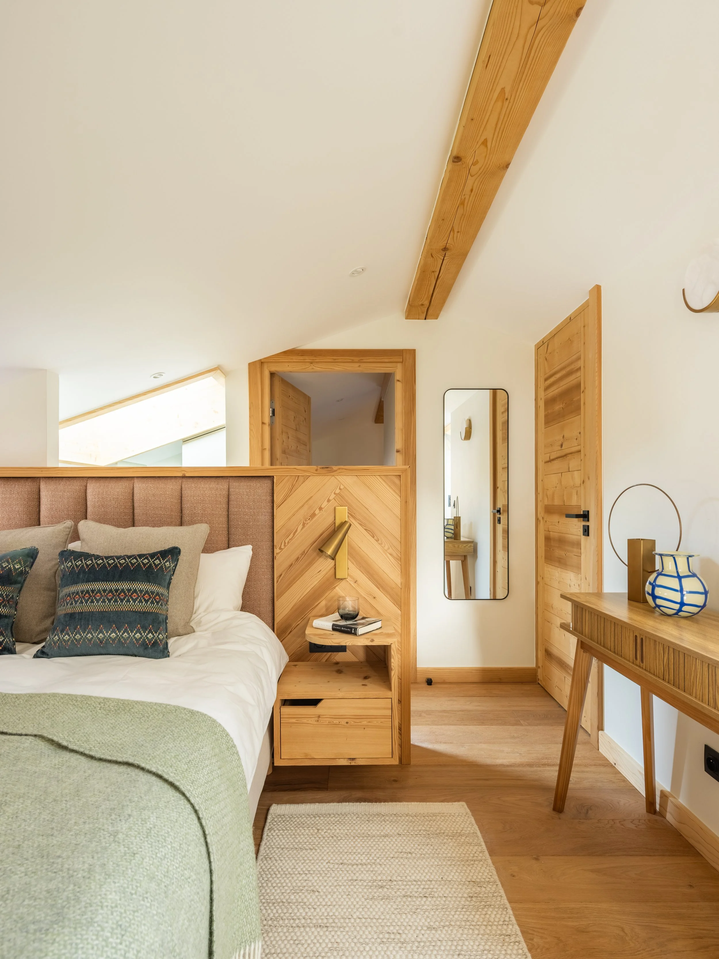 This bespoke headboard incorporates a bedside table and discreet charging points. It complements the natural style of this modern property while being functional. 