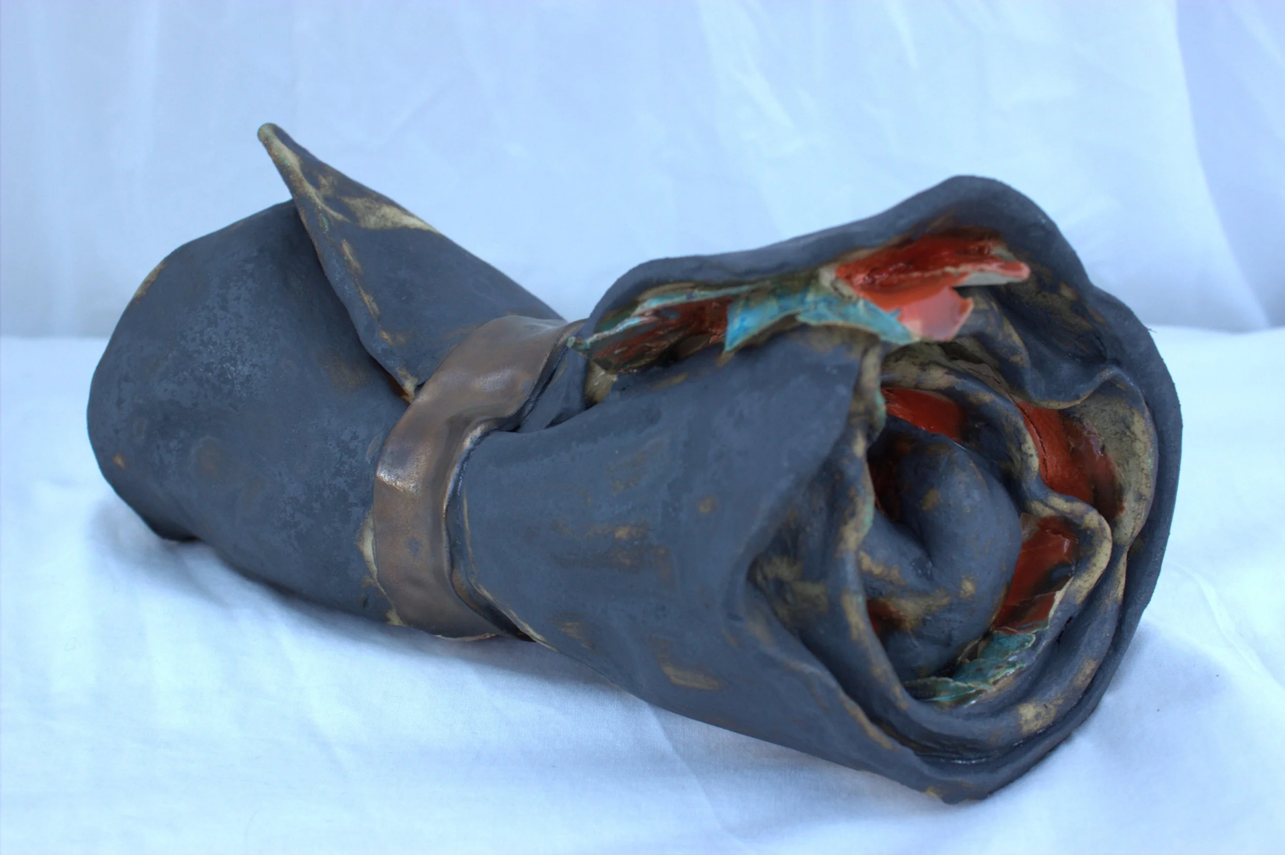 Ceramic sculpture of a rolled up  case concealing a trapped figure