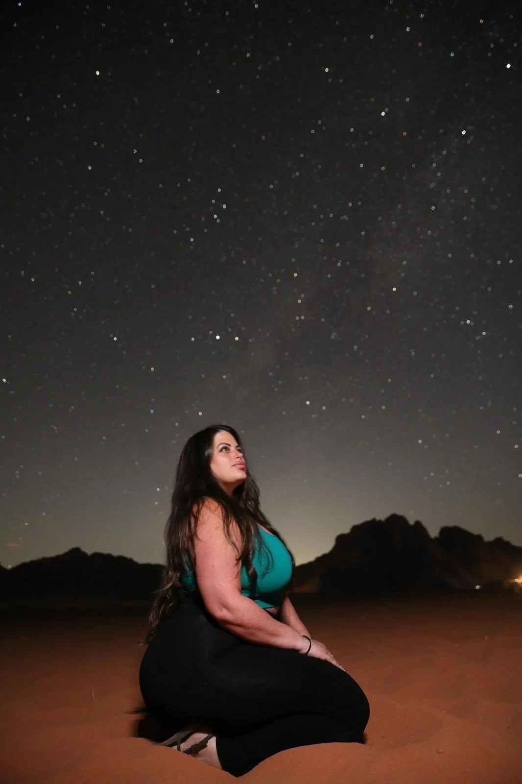 Star-filled night sky above the desert landscape of Wadi Rum, Jordan.