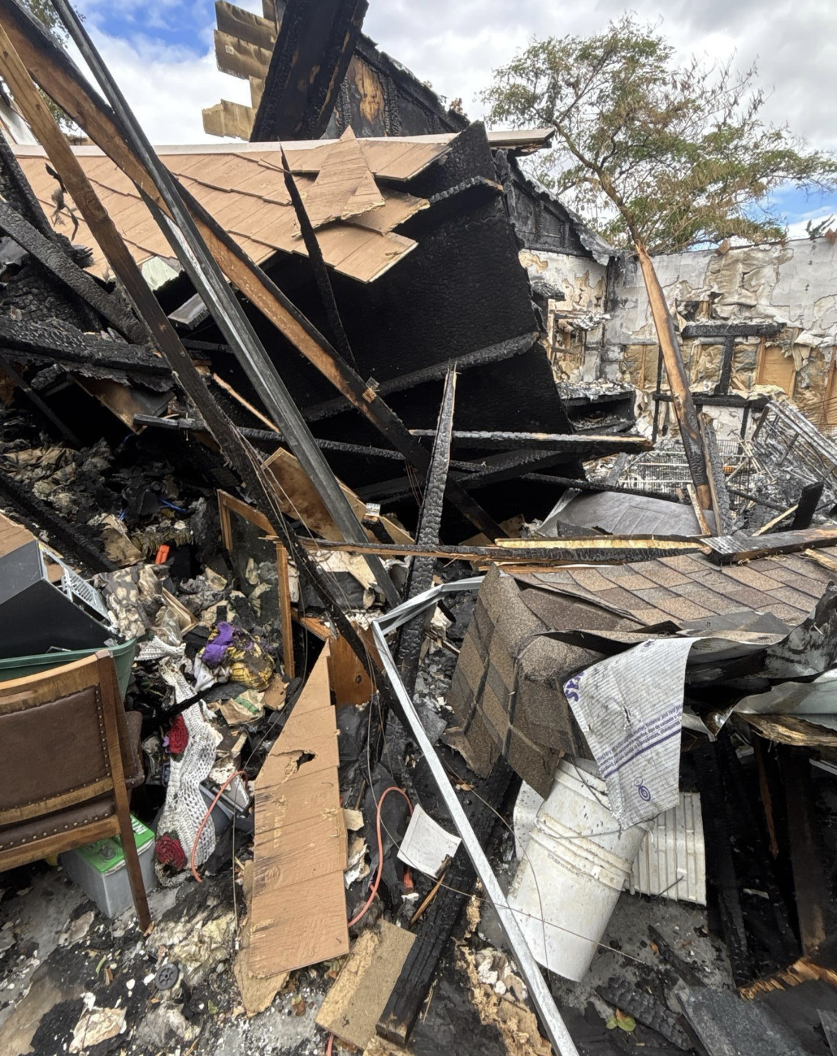Debris and destruction from a fire, including charred and burnt building materials, shattered items, and furniture amidst rubble.