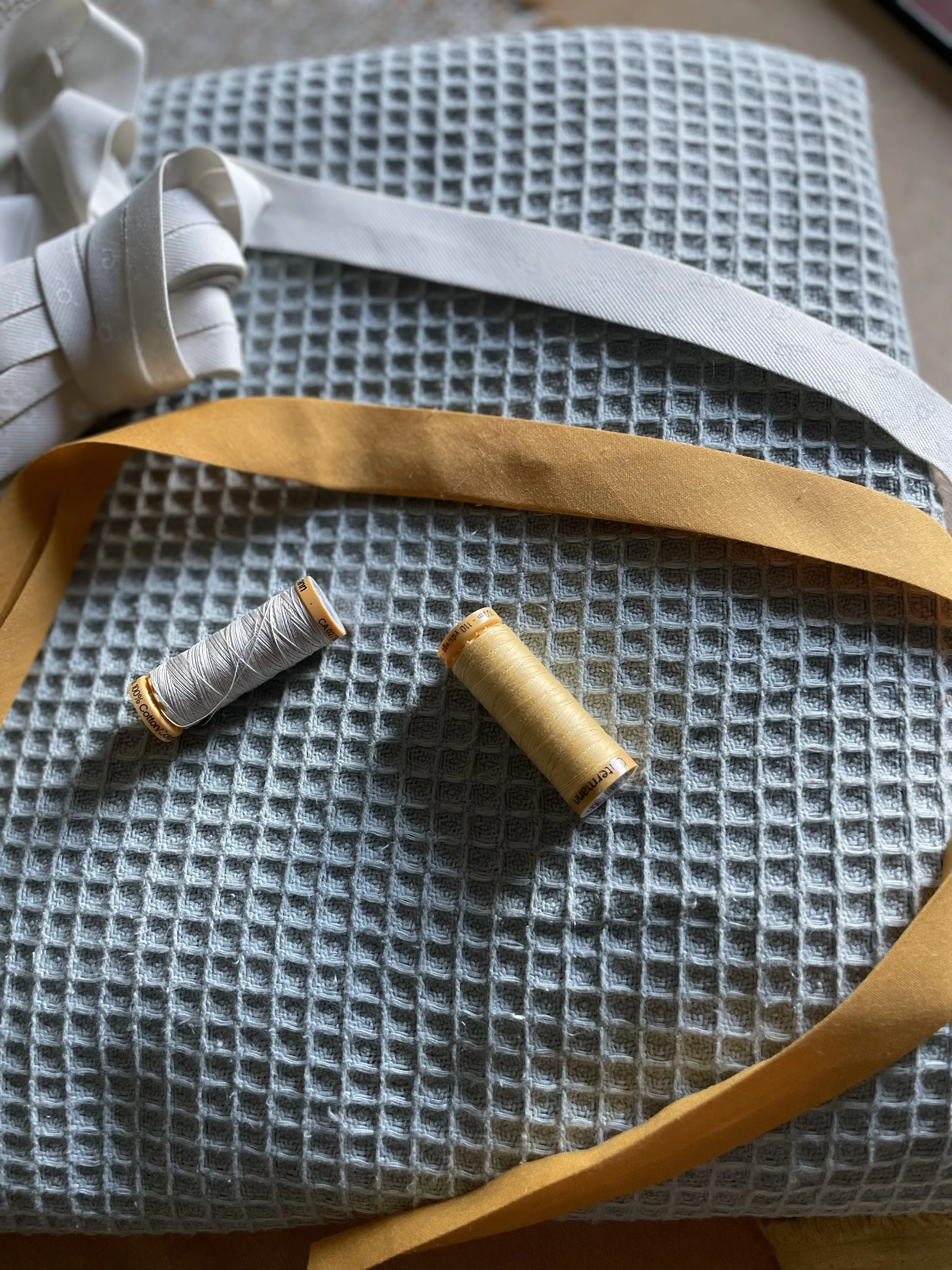 Épingles de couture, rubans et tissu en molleton gris avec boutons dorés