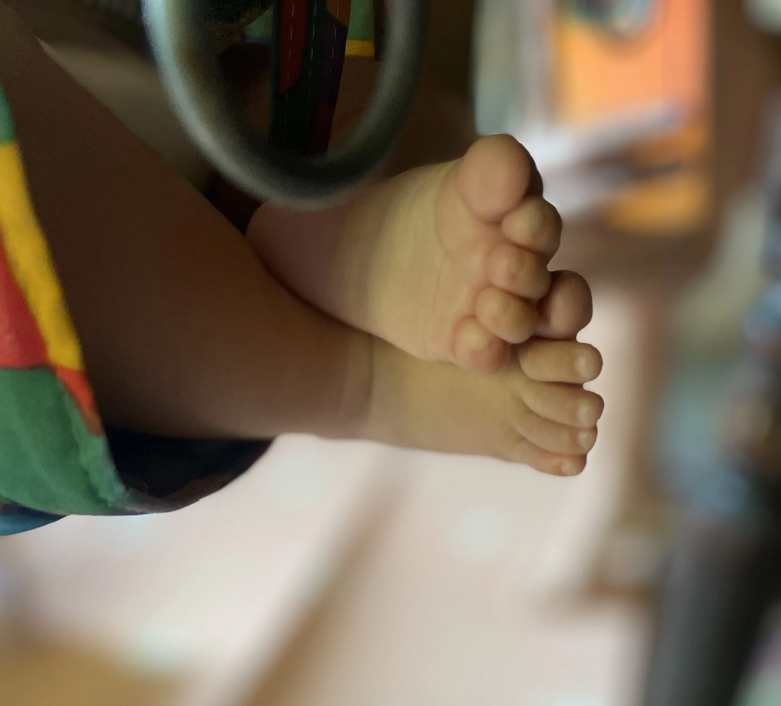 Petite personne portant un short coloré, vue de derrière, avec les jambes et les pieds à l'appui, les jambes reposant sur une surface horizontale.