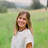 Young woman with blonde hair smiling outdoors in a grassy field