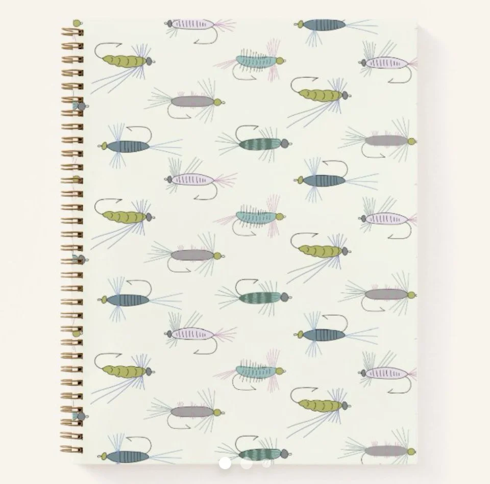 A notebook page with a pattern of colorful fishing flies used for fly fishing, arranged in various orientations.