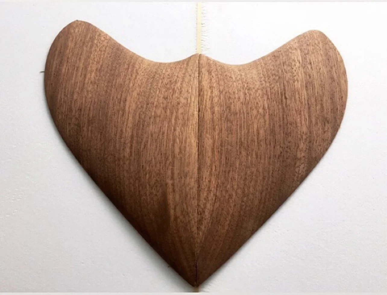 A wooden heart-shaped object with a natural wood grain pattern against a white background.