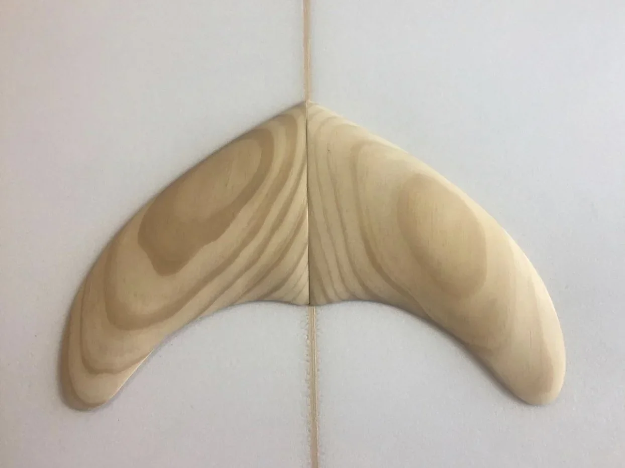 Two wooden wall decorations shaped like whale fins or flippers, mounted on a corner wall.