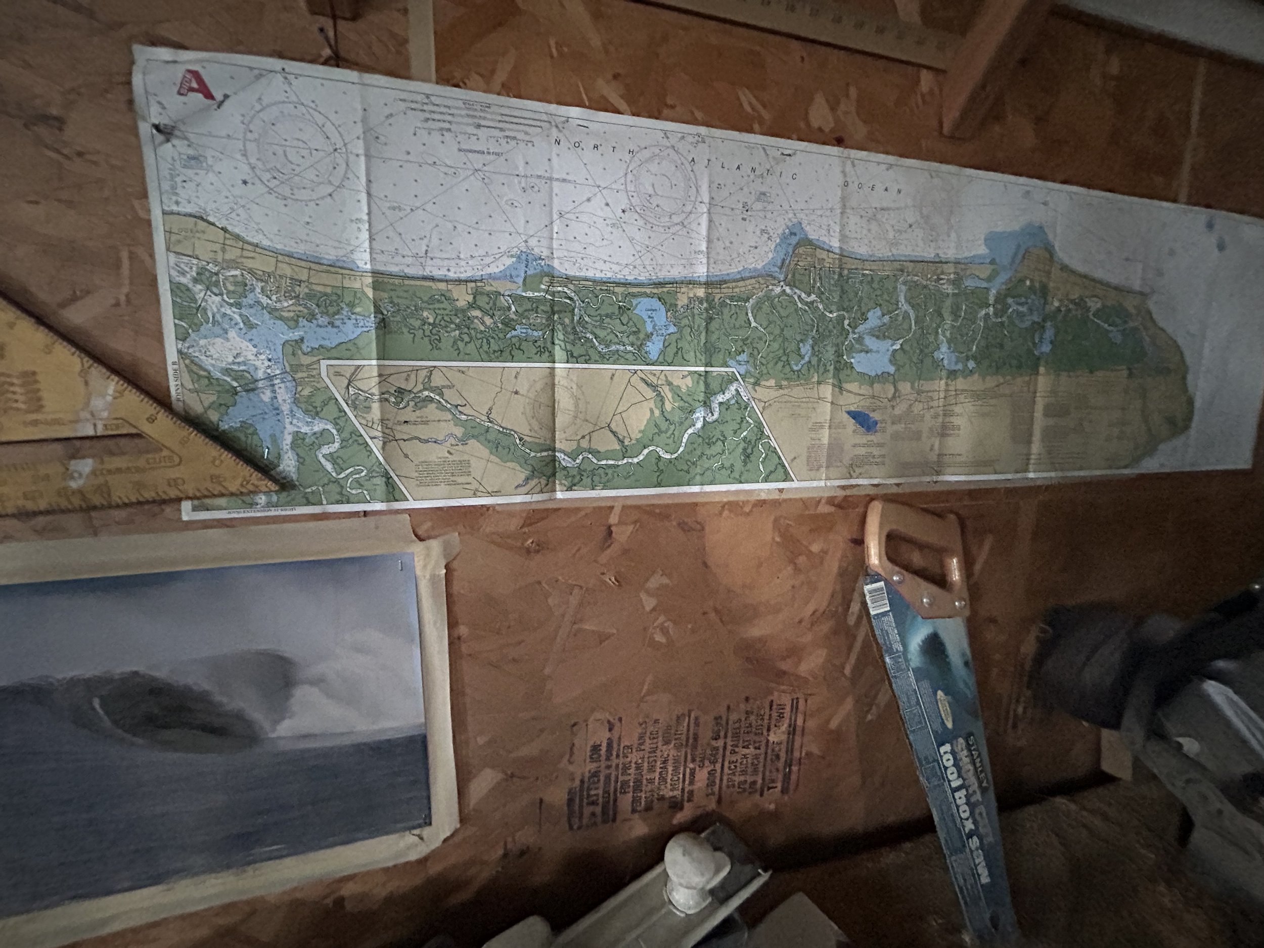 A map of a coastal area showing waterways, land, and topography, laid out on a wooden surface with other tools nearby. South New Jersey