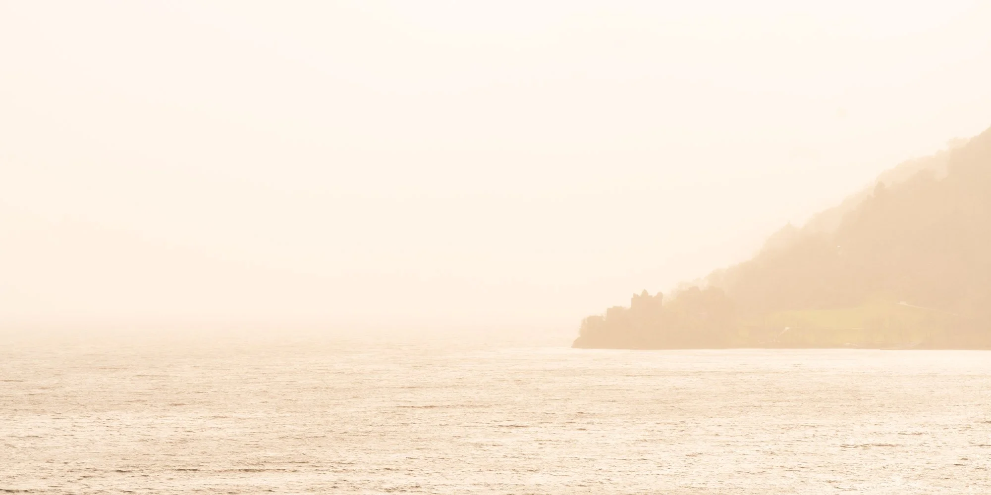 Golden sunlight illuminates the cloud and rain at Urquhart Castle on Loch Ness, Drumnadrochit, Scotland