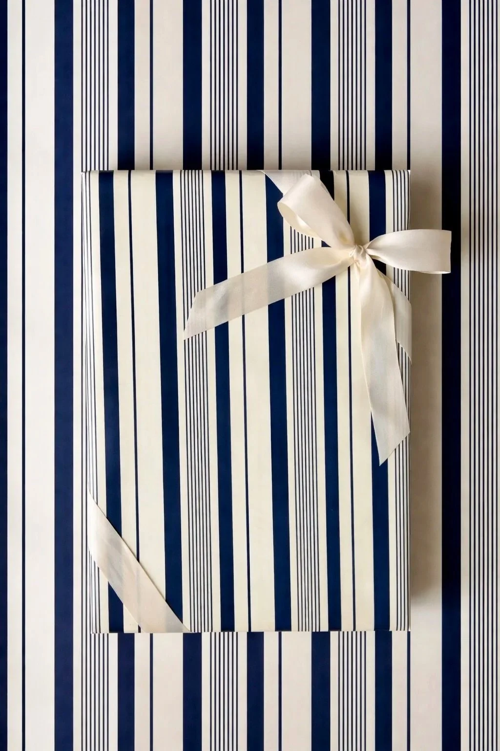 A gift wrapped in striped blue and white paper with a white ribbon tied in a bow.