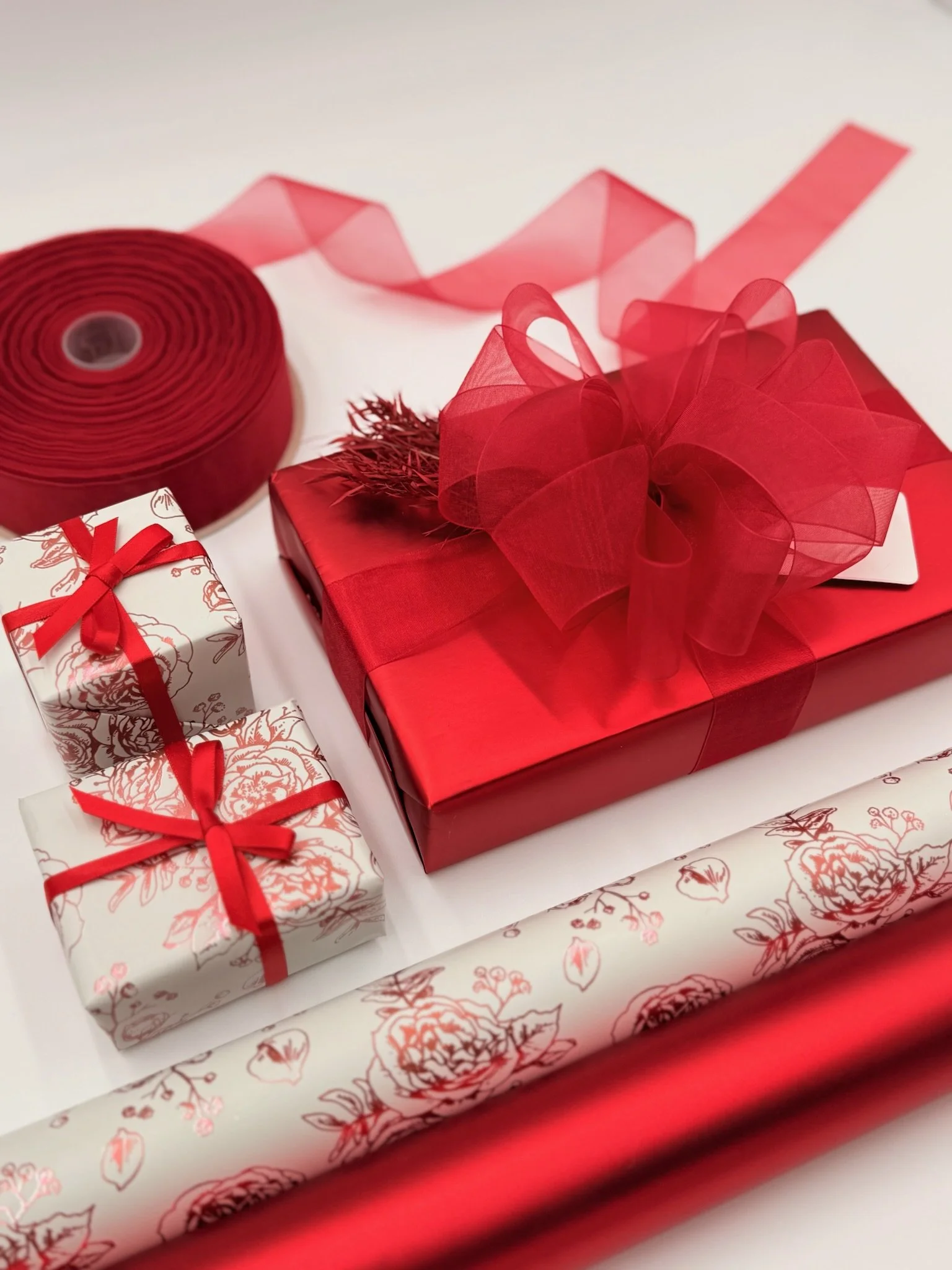 Red and white wrapped gift boxes, a large red gift with a bow, red ribbon, and decorative wrapping paper.