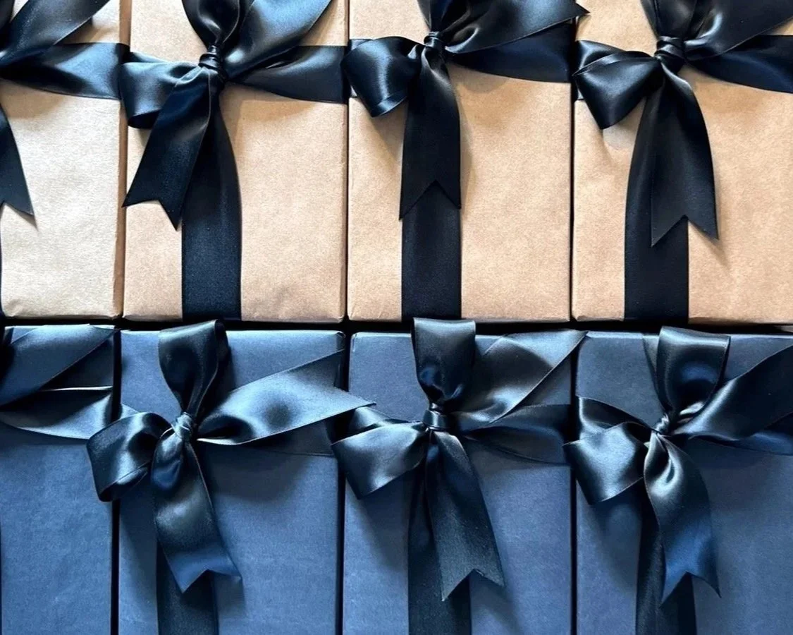 A coordinated group of kraft and navy gifts tied with dark blue bows.
