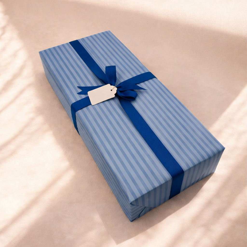 A rectangular gift wrapped in blue and white striped paper, tied with a blue ribbon bow, with a blank white gift tag attached.