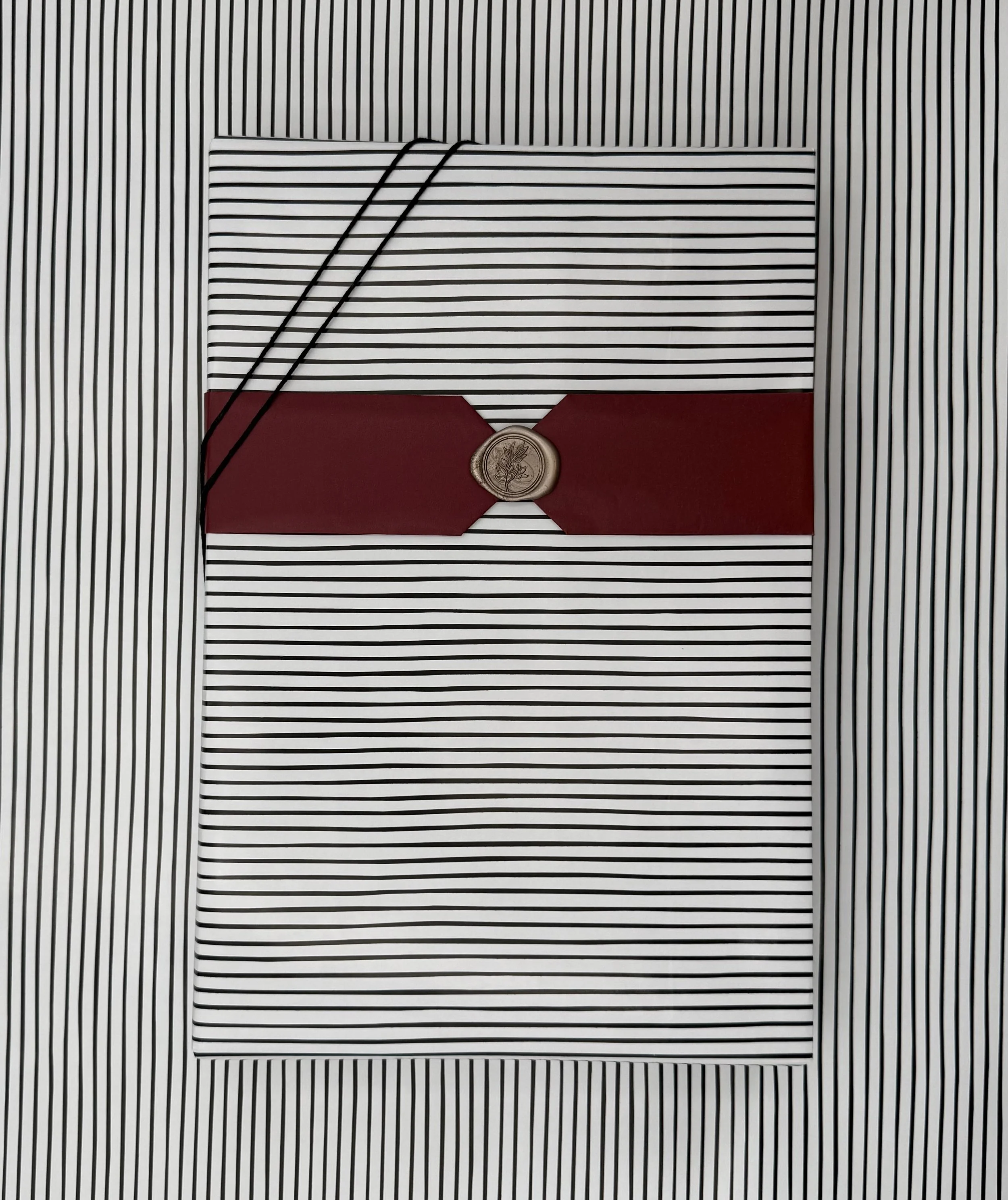 A striped envelope with a red band and a seal, placed on top of a matching striped background.