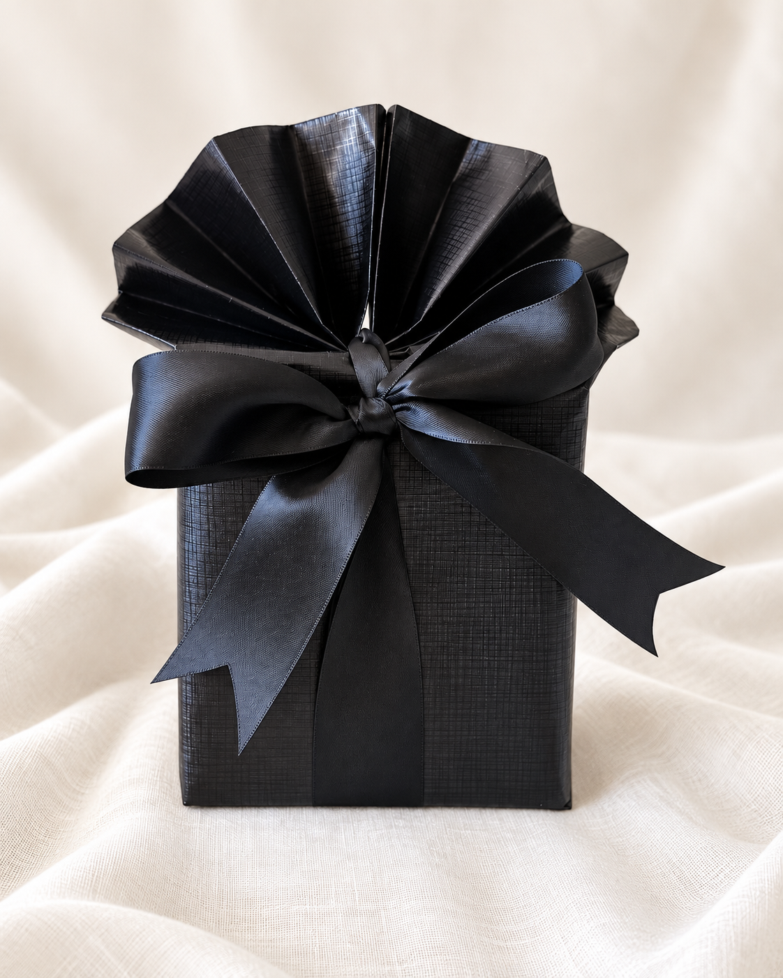 Black gift with a gathered paper top and black ribbon bow.