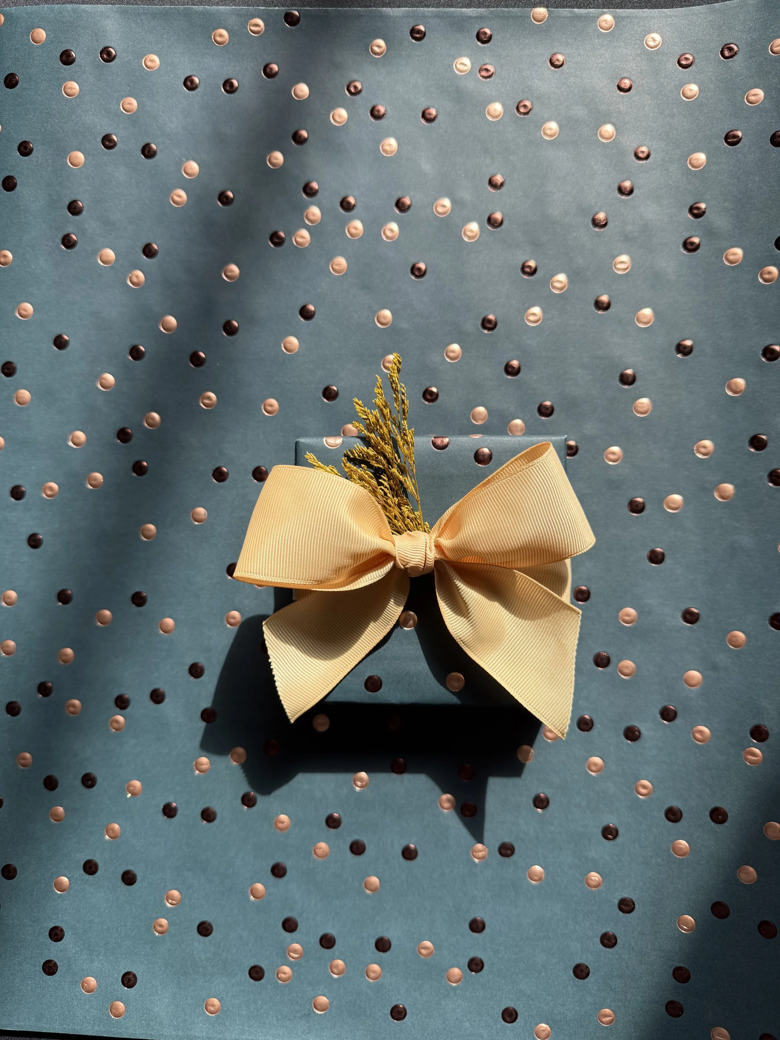 Dark blue gift with a gold bow on blue paper with gold dots.
