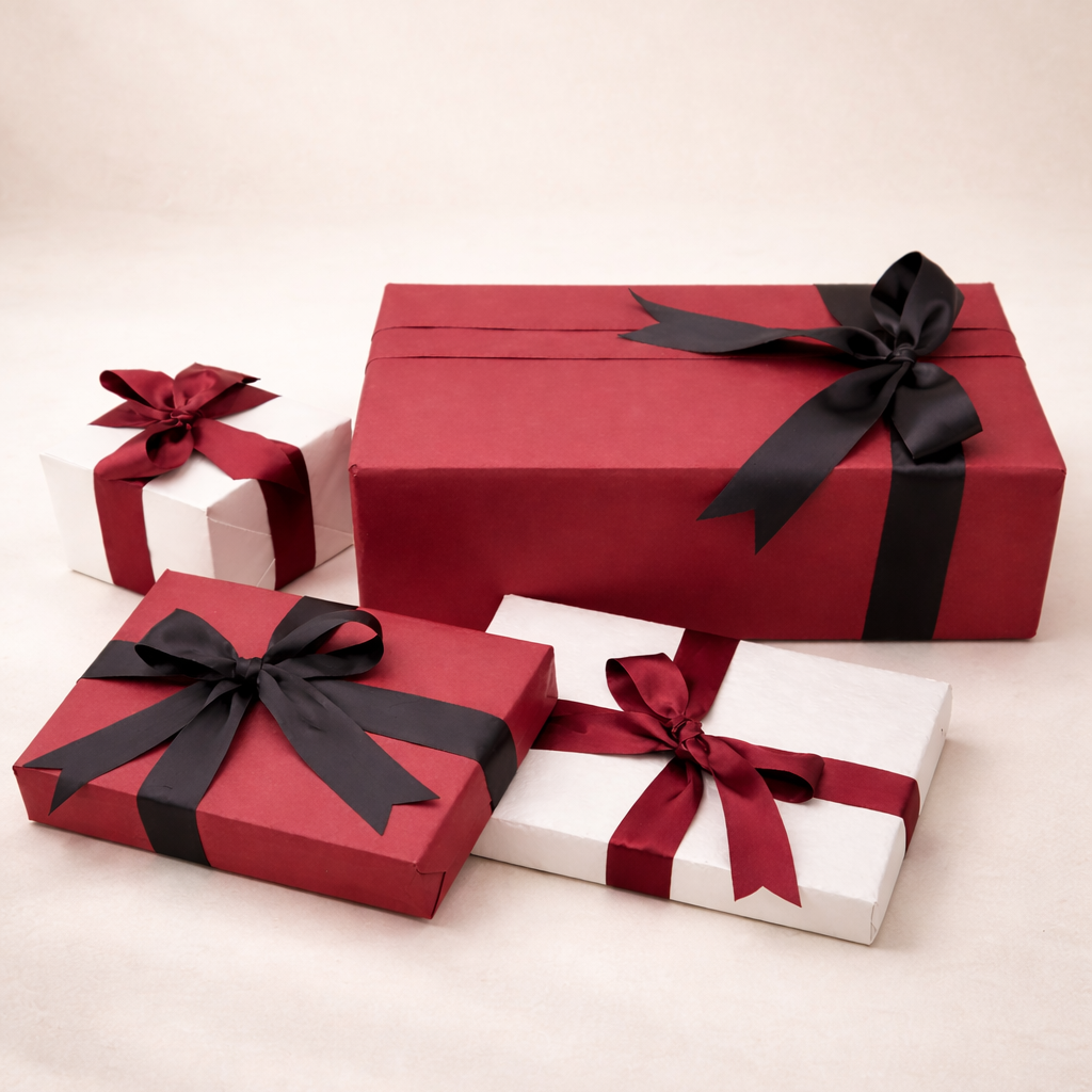 Four wrapped presents in red, white, and black paper with ribbons, on a light background.