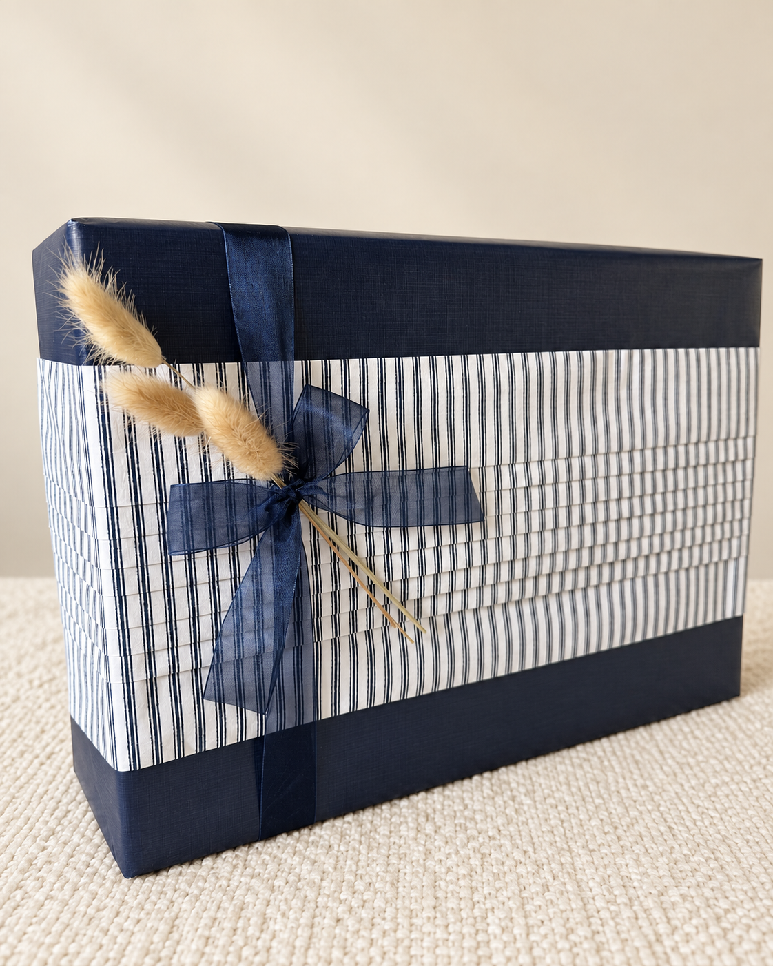 Navy and striped gift wrap with a blue bow and dried grasses.