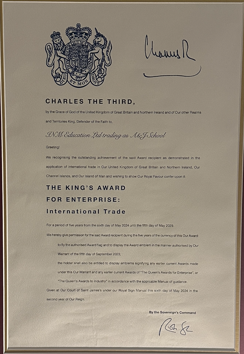 A certificate of achievement awarded to INM Education Ltd trading as Ace J School from the Queen's Royal Command, signed by a monarch's signature, with a royal crest at the top.