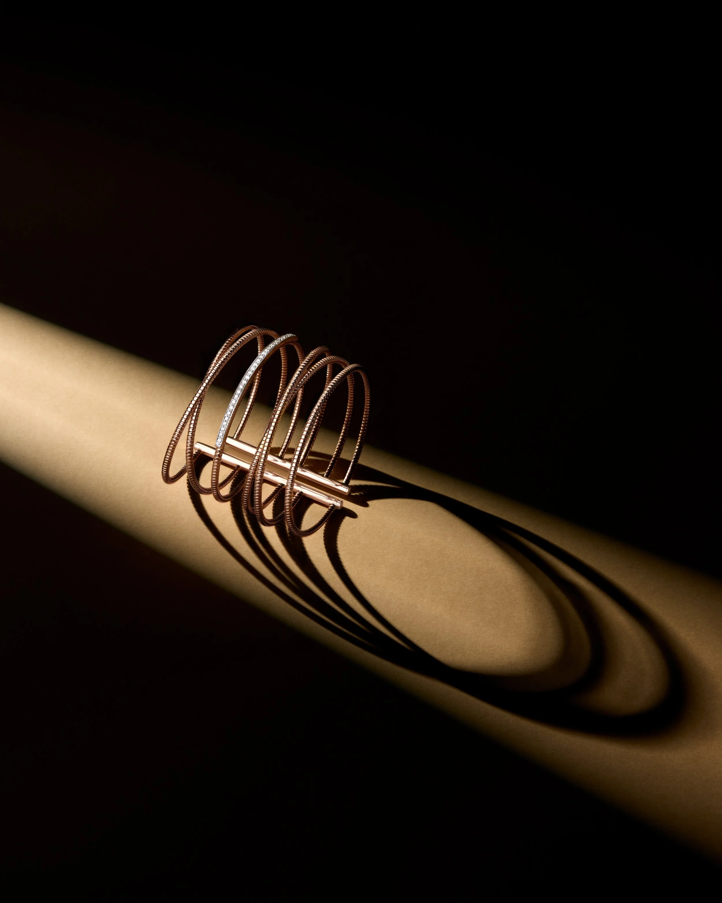 Close-up of a modern copper spiral ring with shadows cast on a beige surface.  K di Kuore jewelry.