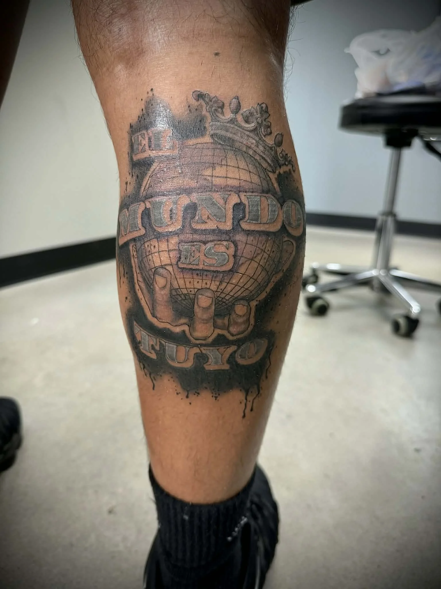 Spanish writing tattoo on calve placement. Hand holding the world tattoo.