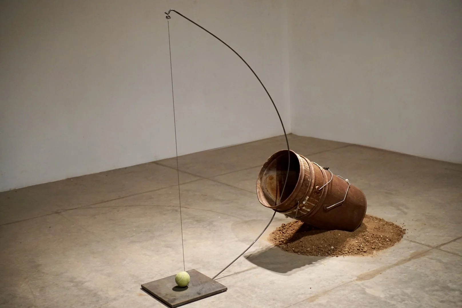 Sound of a Bow String, Metal plate, tennis ball, aircraft wire, metal rod, three rusted buckets, dirt, 58x12x57 in, 2025