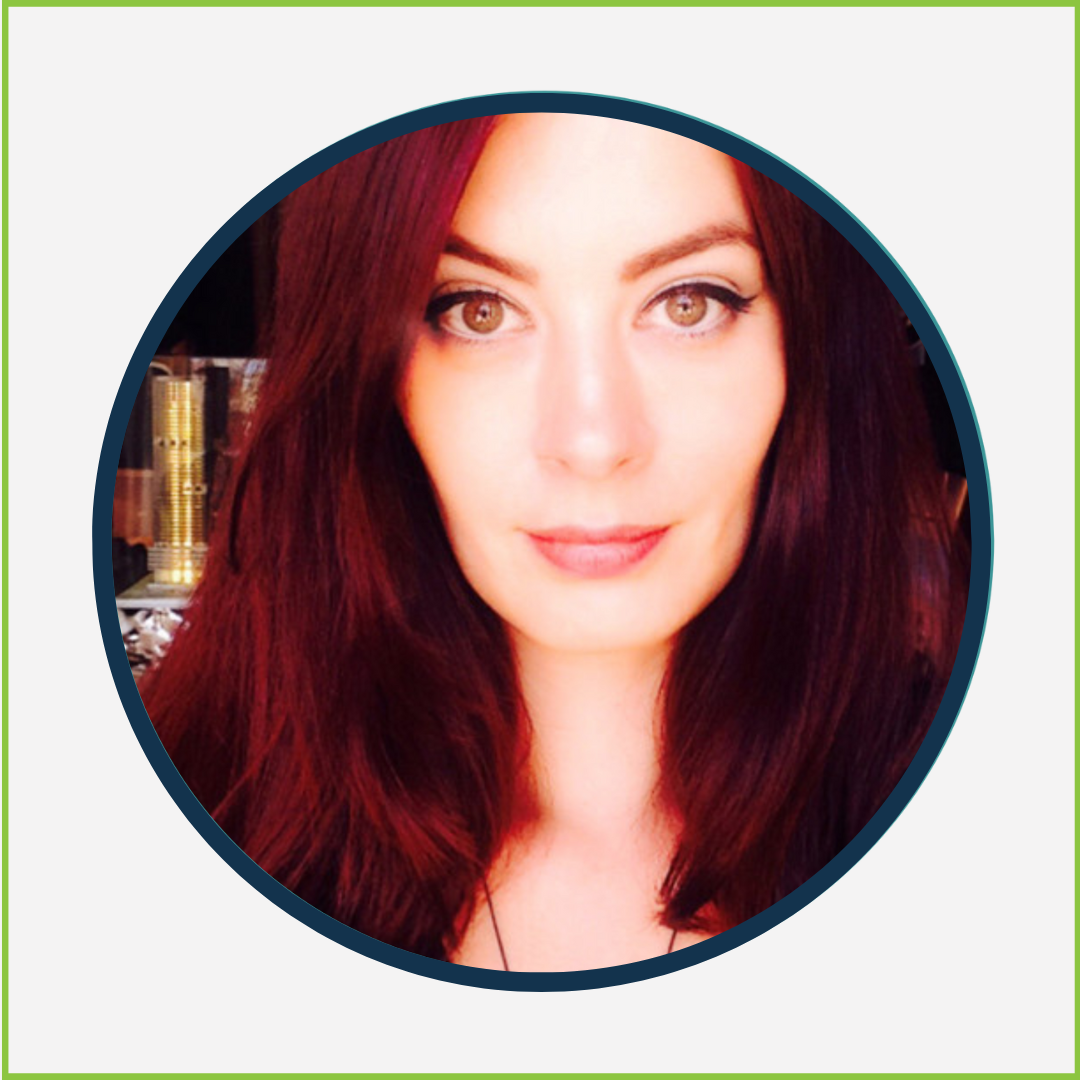 A woman with long, dark red hair and brown eyes looking at the camera with a slight smile.