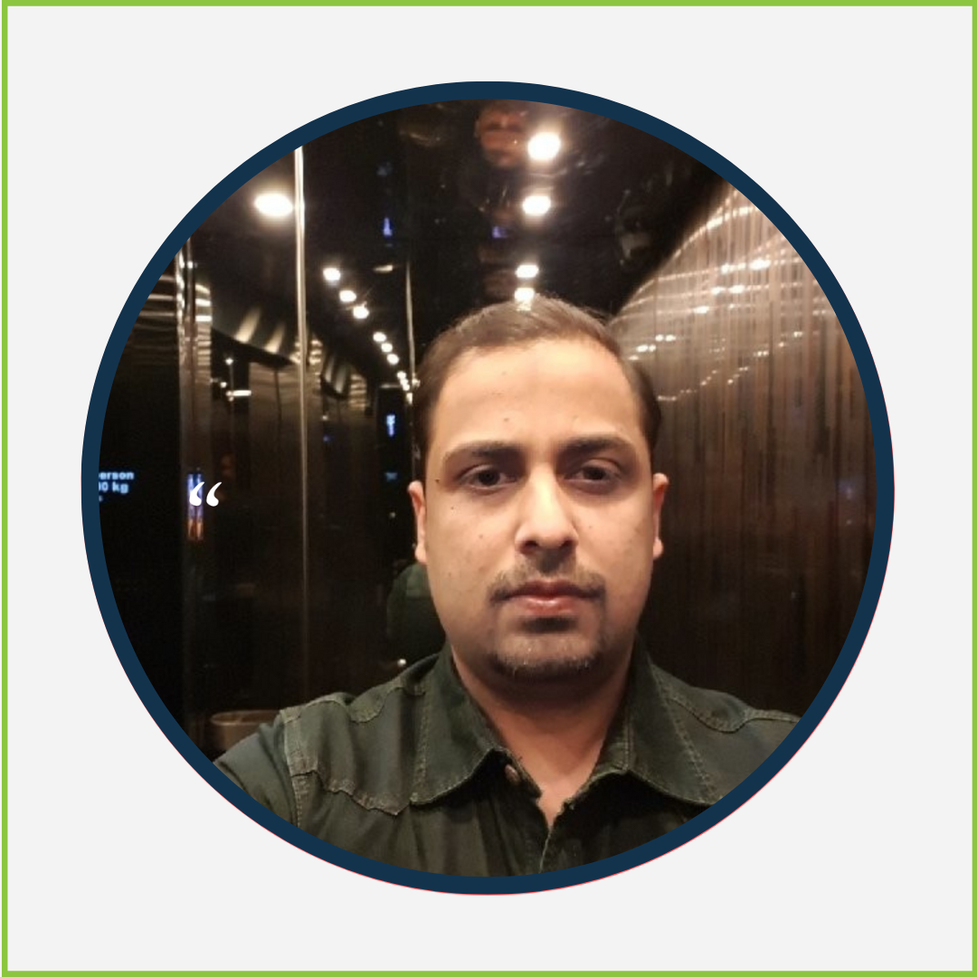 A young man taking a selfie in an elevator with dark walls and ceiling, reflecting lights, wearing a dark green shirt.