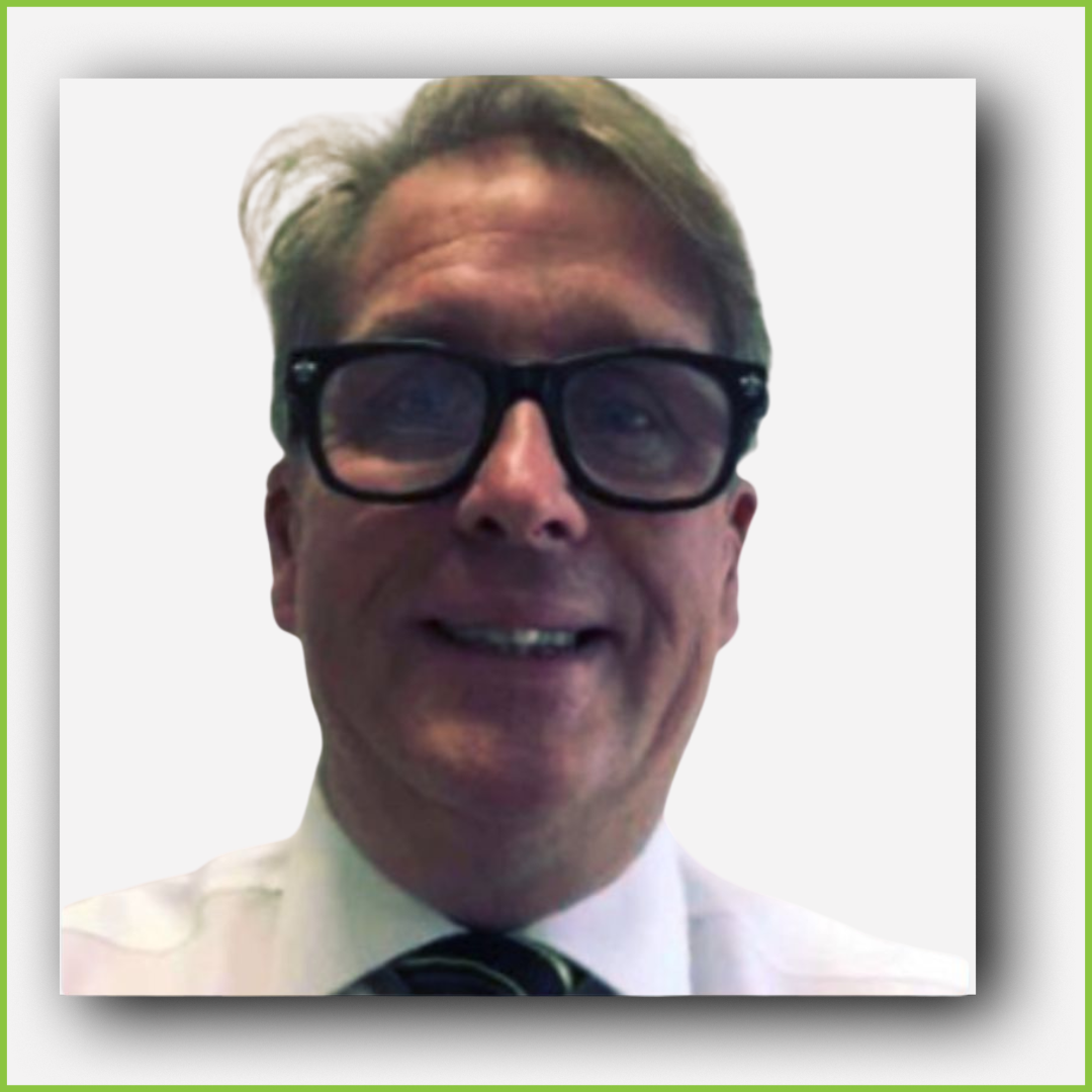 A man with gray hair, wearing black glasses, a white shirt, and a striped tie, smiling at the camera.