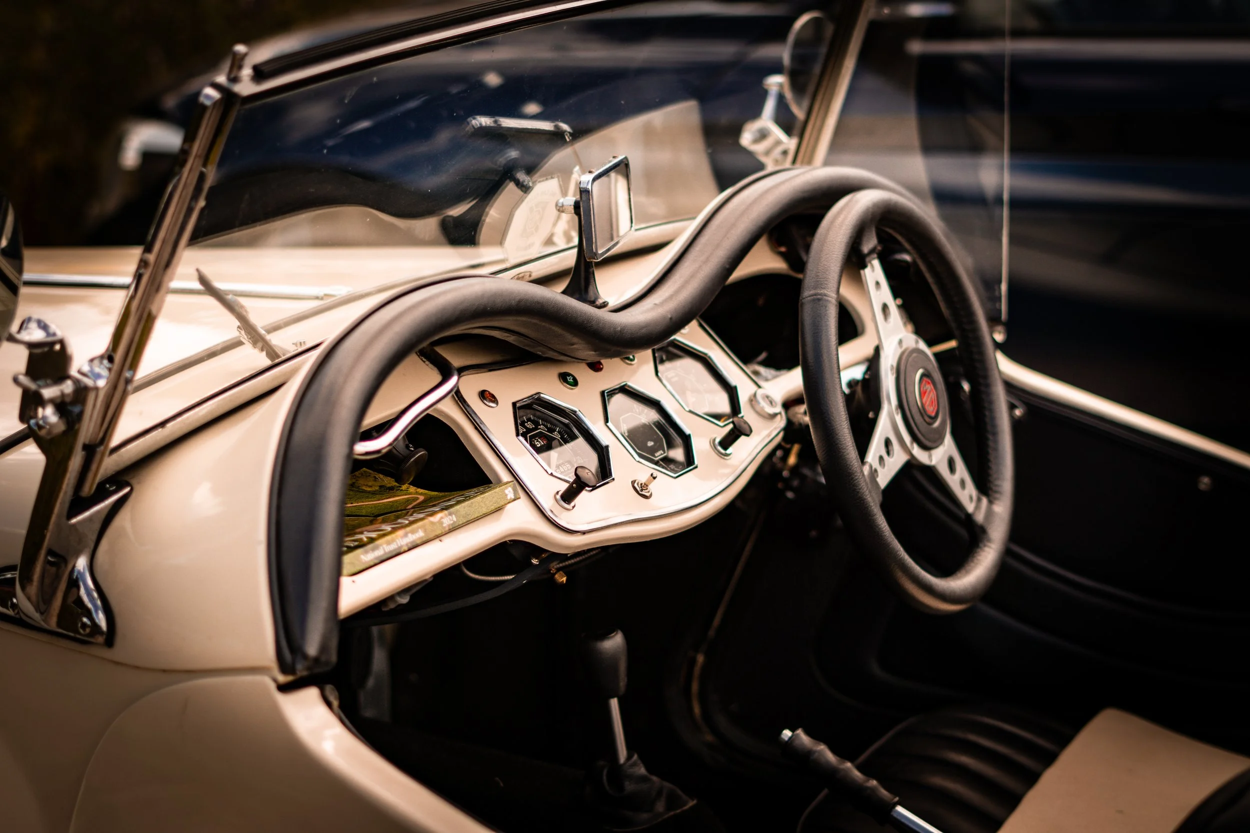 Close-up of the interior of a vintage convertible sports car, showing the dashboard with analog gauges, a steering wheel, and a gear shift.