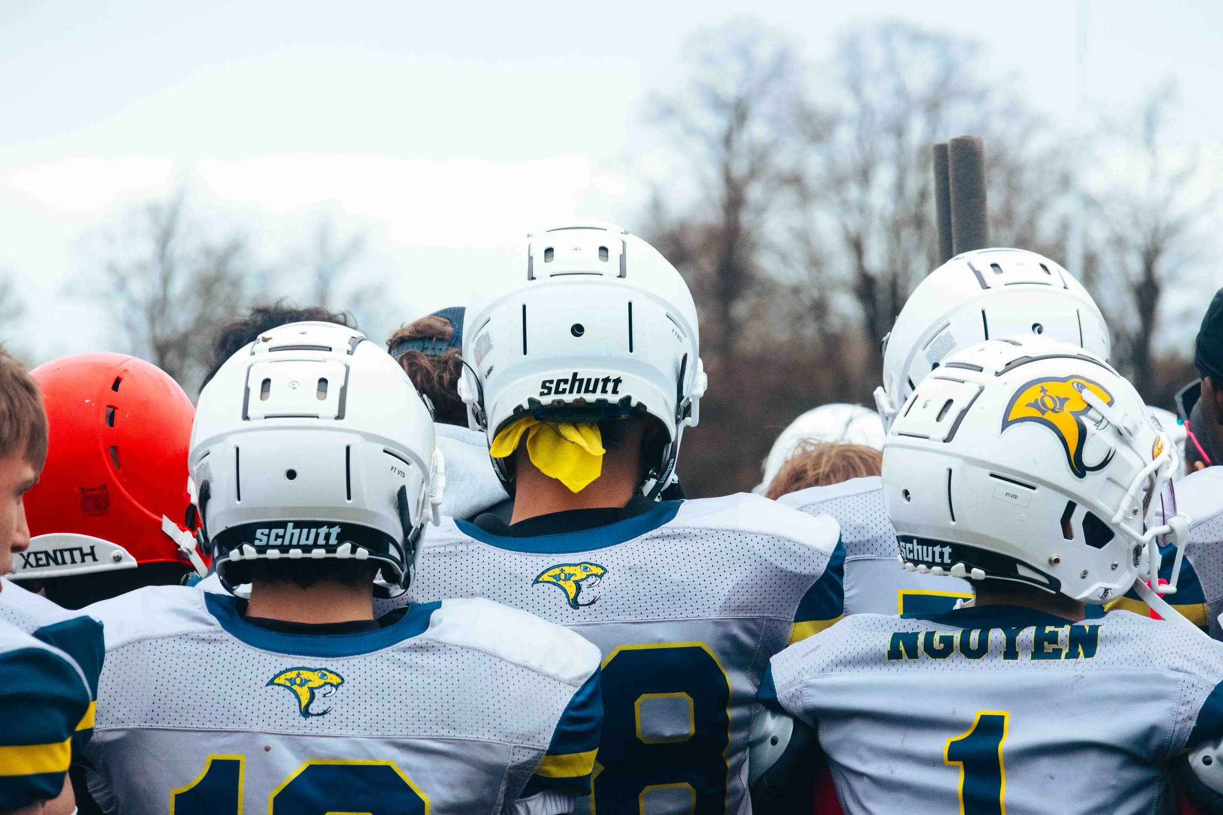 A group of American football players from the Los Angeles Chargers, wearing white helmets and jerseys with yellow and blue accents, standing together on a football field outdoors.