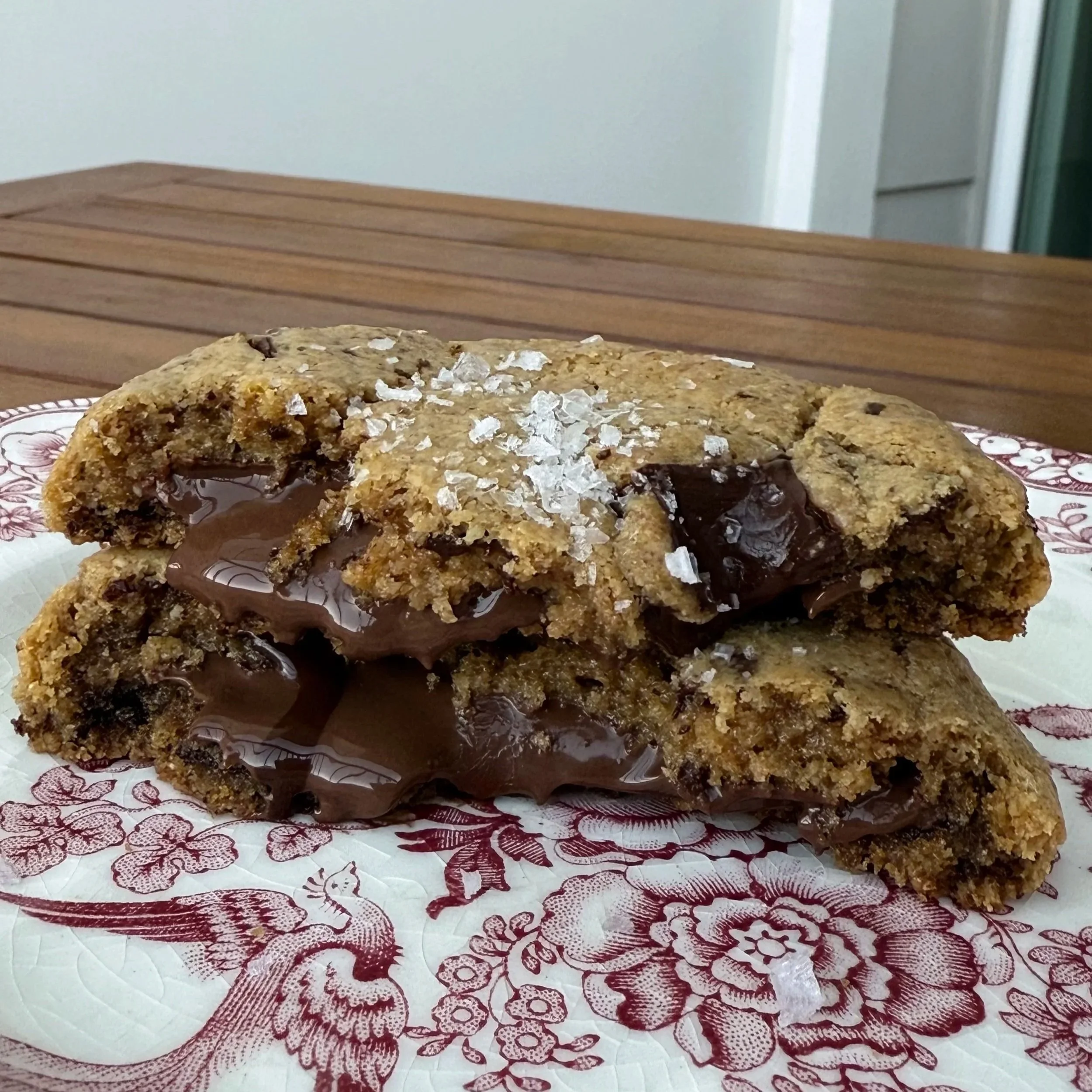 Chocolate chip cookie with melted chocolate and sea salt on top, broken in half