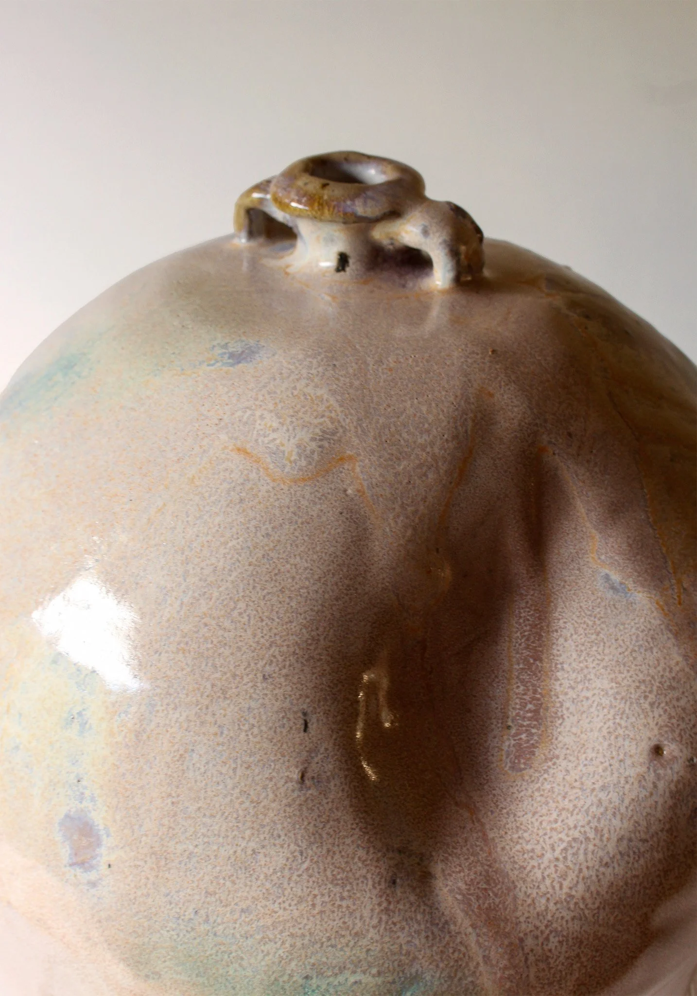 Close-up image of a ceramic object with a textured, speckled surface and a small opening on top.