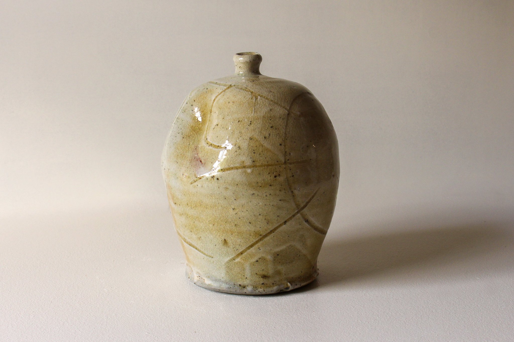 Yellow-coloured ceramic vase with a small neck and a rounded body, featuring visible crackle glaze and subtle line decorations.
