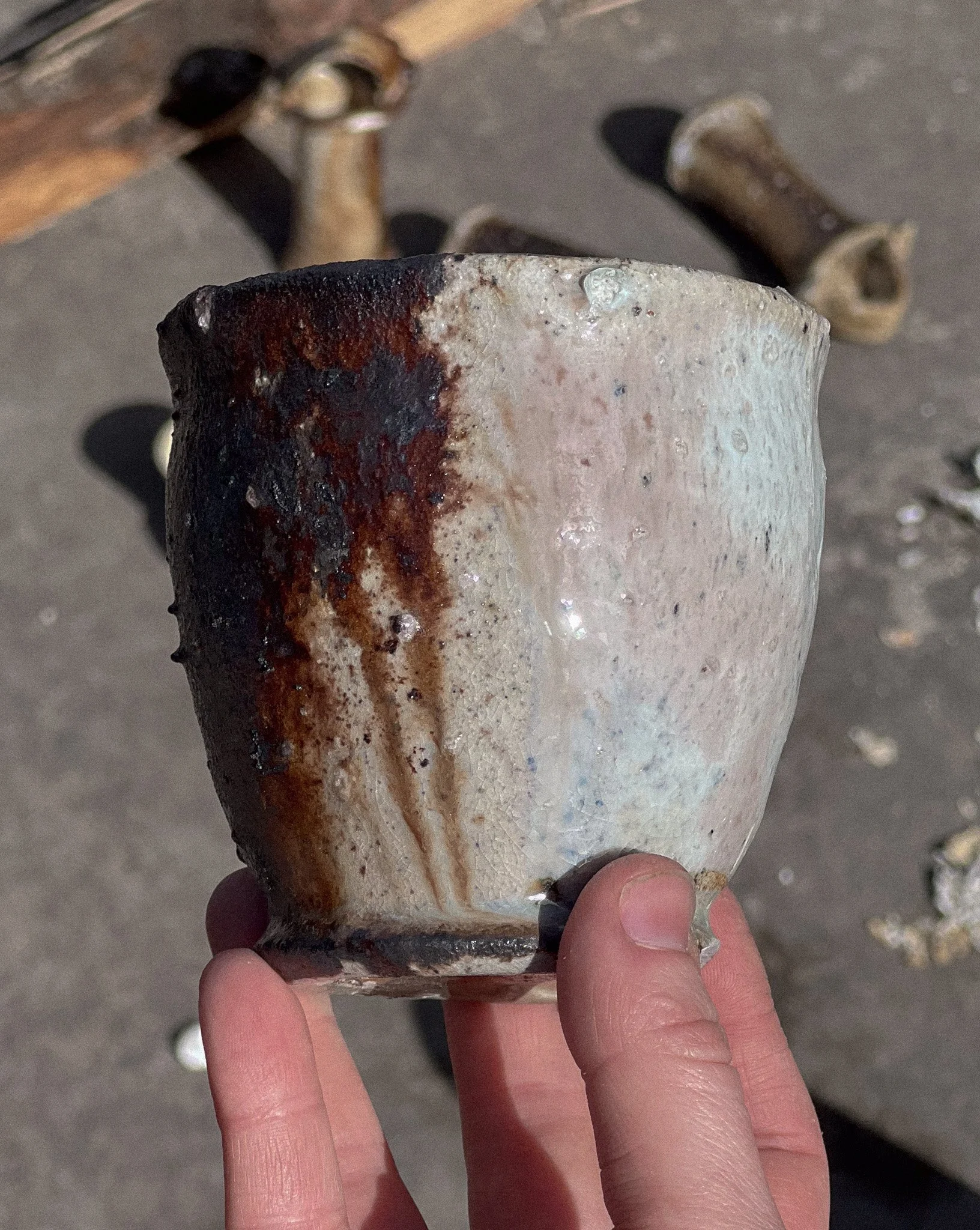 Close-up of a person's hand holding a rough, ceramic beaker.
