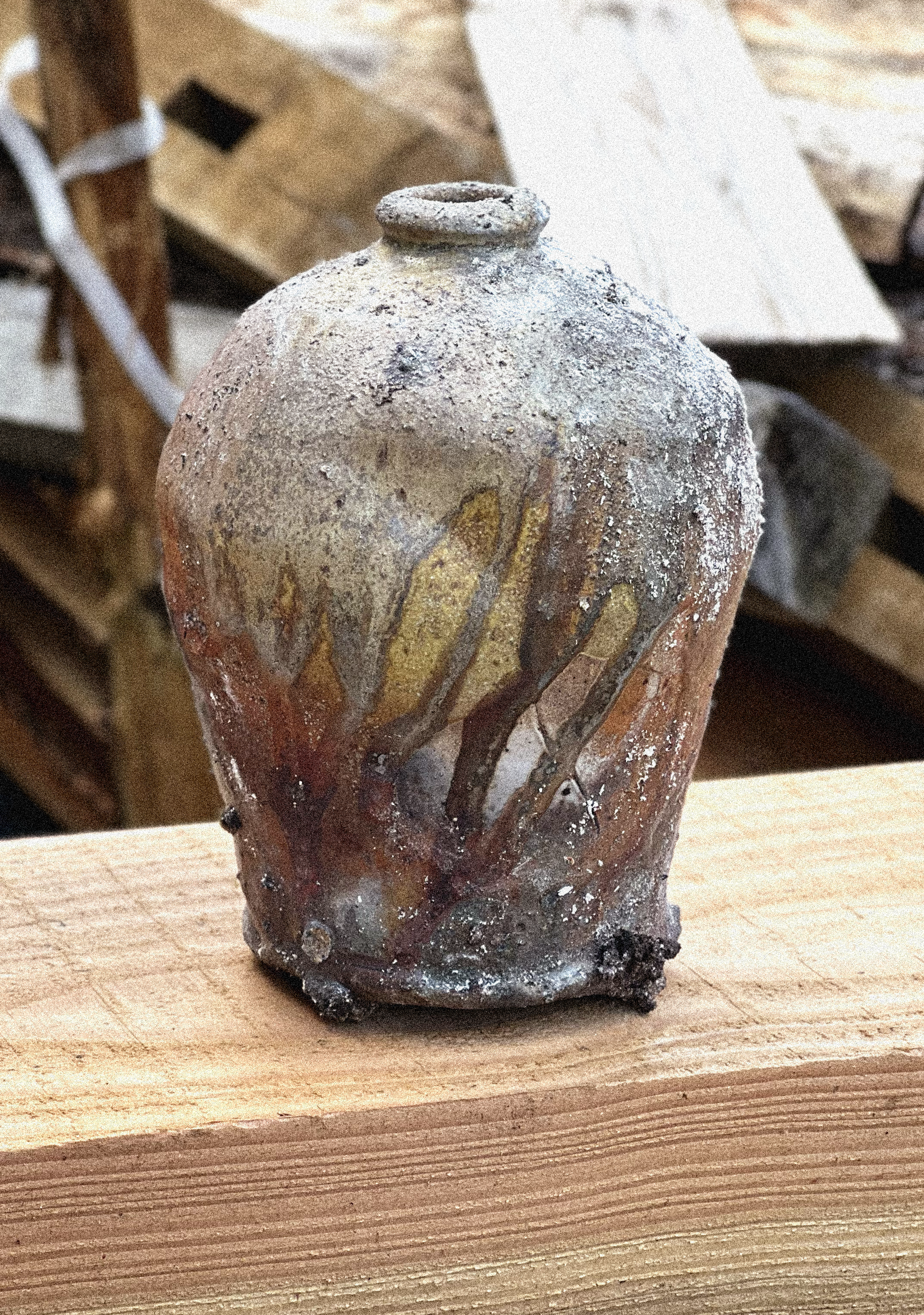 Close-up of a small, irregularly shaped, textured ceramic item or sculpture on a wooden surface.