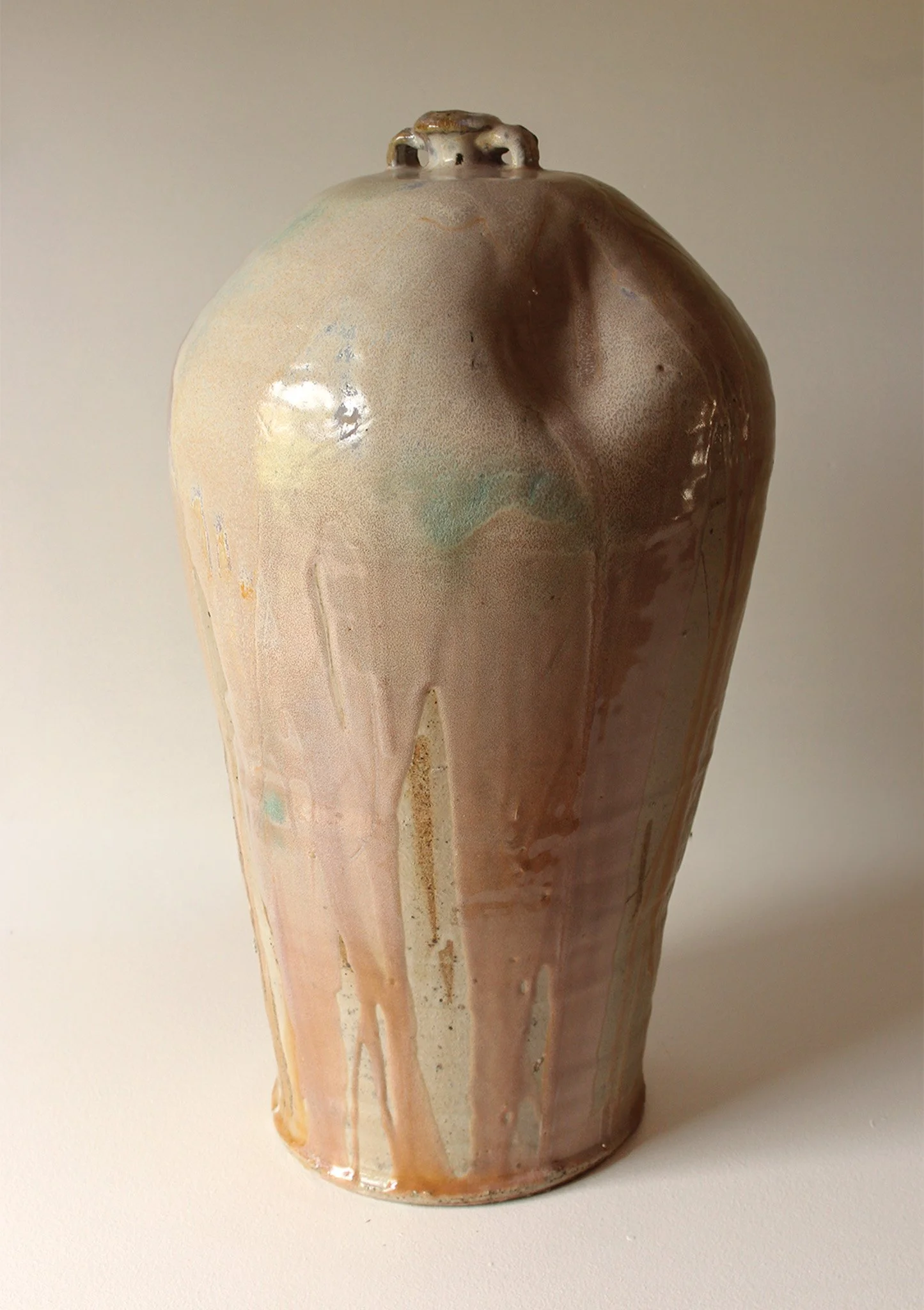 Ceramic vase with a smooth surface, glazed in pink, orange, blue, and brown colours with flowing drip glaze design.