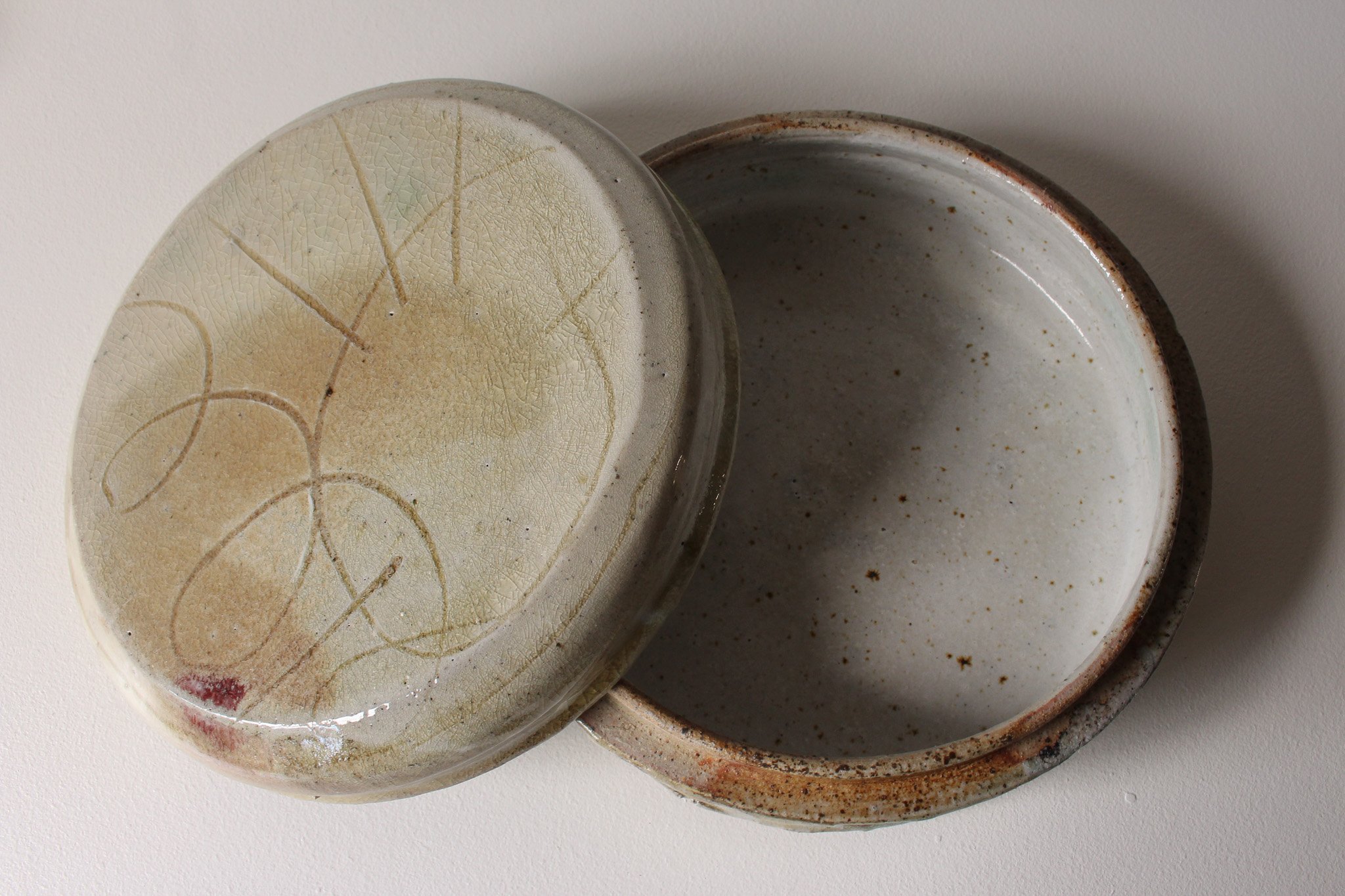 Close-up of a ceramic box with earthy tones and textured surfaces,  with a yellow and brown glaze.