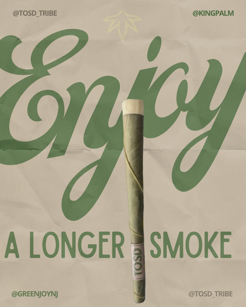 A hand-rolled joint standing upright in front of a poster with the words 'Enjoy A Longer Smoke' in large green cursive text.