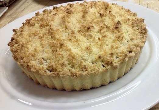 A crumbly baked dessert, possibly a cheesecake, on a white plate.