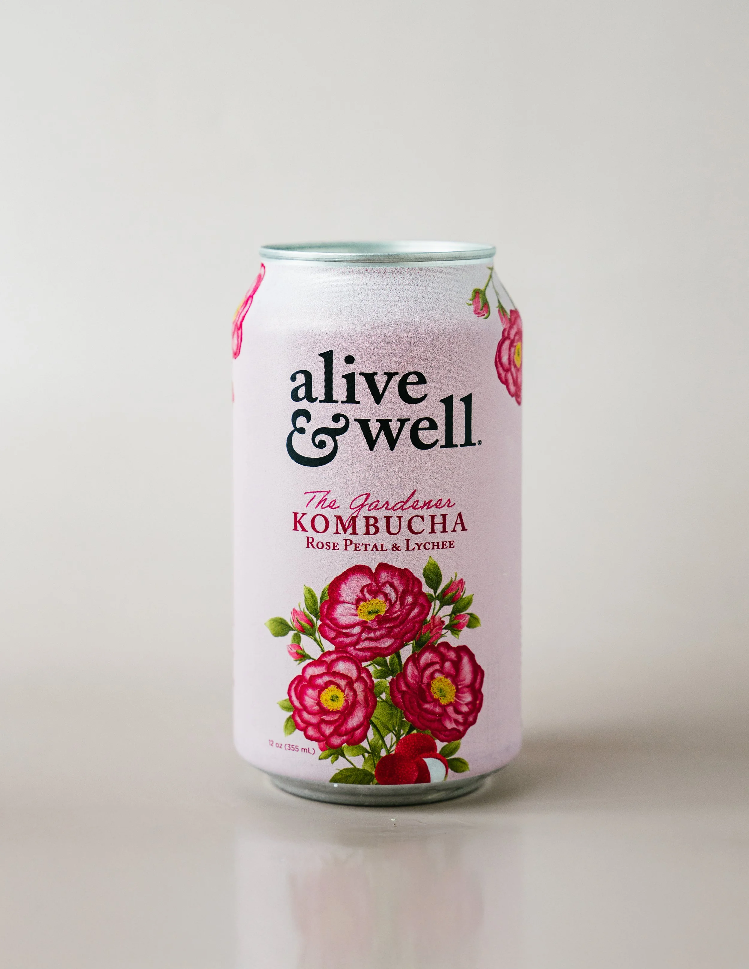 A can of Alive & Well Gardenar Kombucha with rose petal and lychee flavor, featuring illustrations of pink roses and lychee fruit.