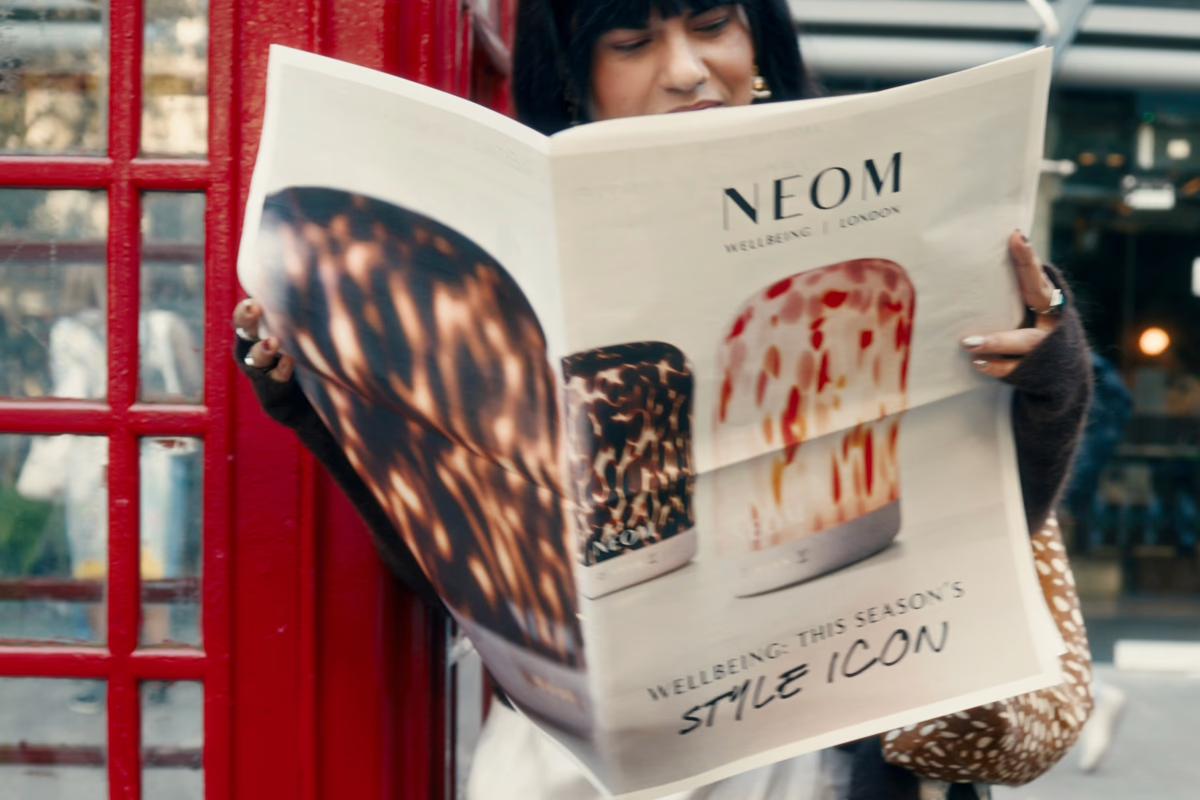 Person is reading a fashion magazine outside near a red British telephone booth. London Fashion Week.