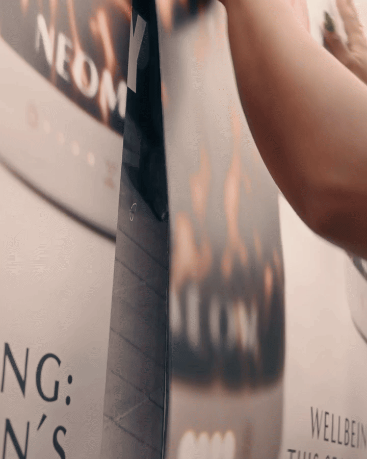 Close-up of a hand holding a magazine or brochure with a blurred background and some text visible.