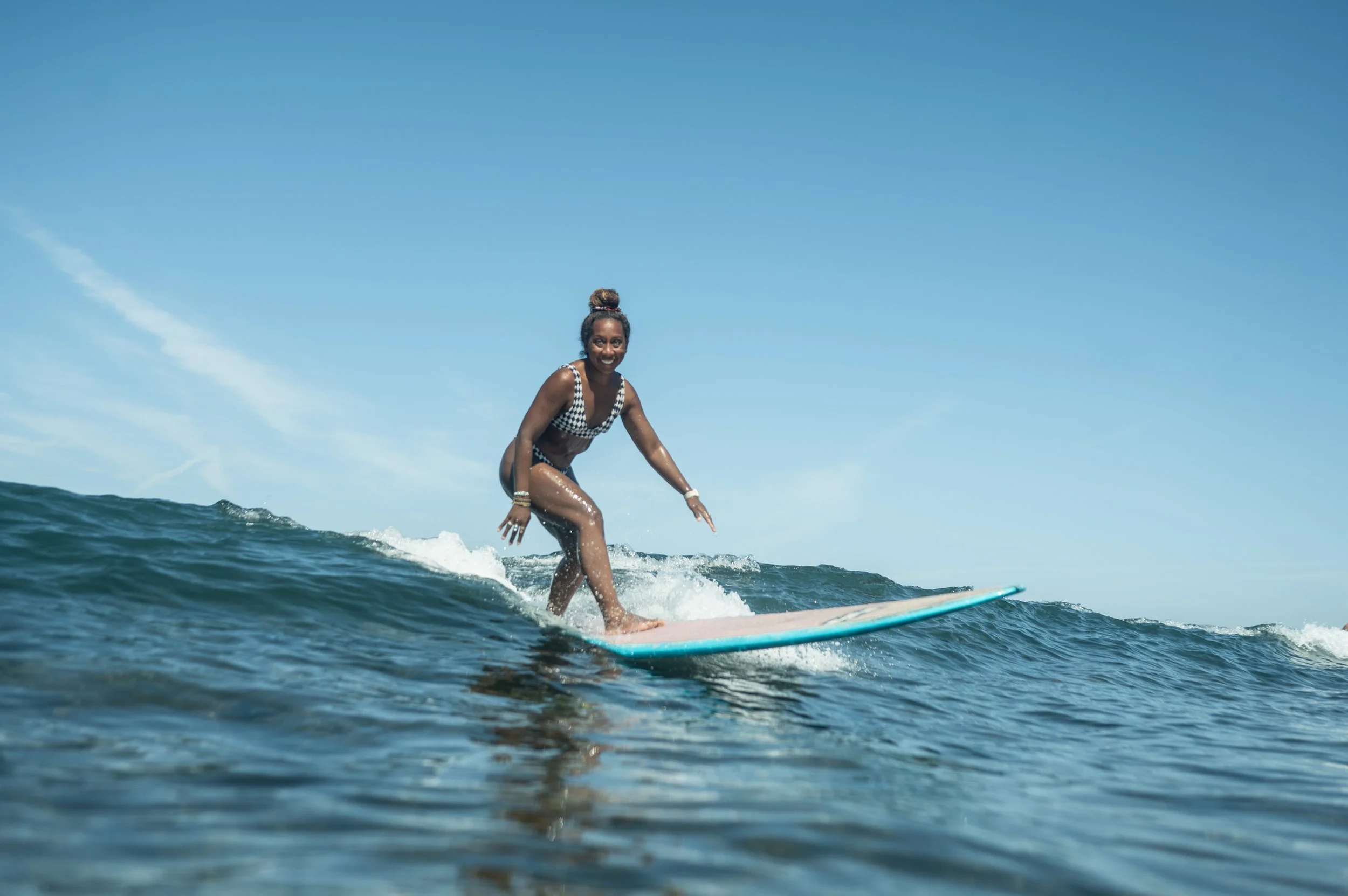 Woman in a swimsuit surfing on a wave in the ocean on a sunny day.