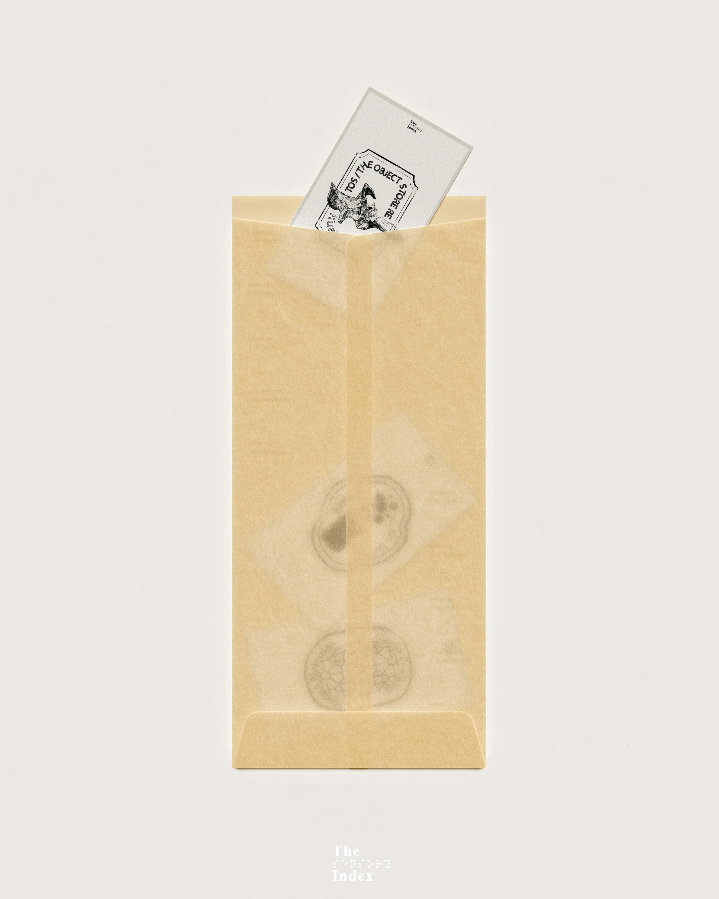 A beige paper bag with two visible black-ink circular stamps and a paper slip with a black-and-white illustration of a dog and the text "TO THE OBJECT STORE".