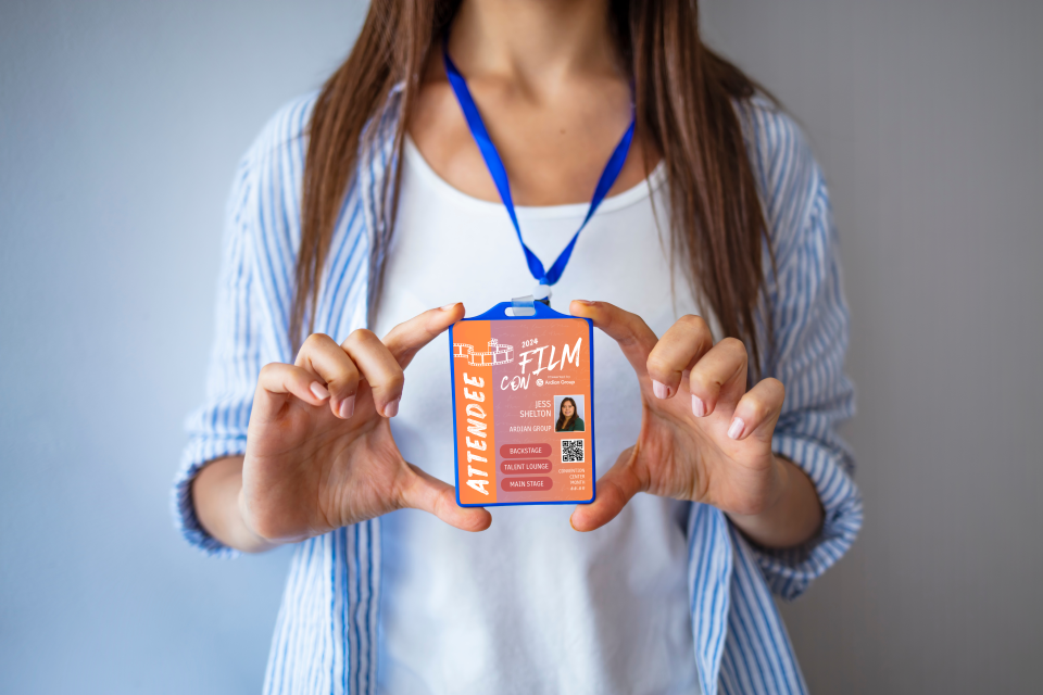 Person holding a film festival attendee badge with event details and a photo, wearing a blue lanyard.