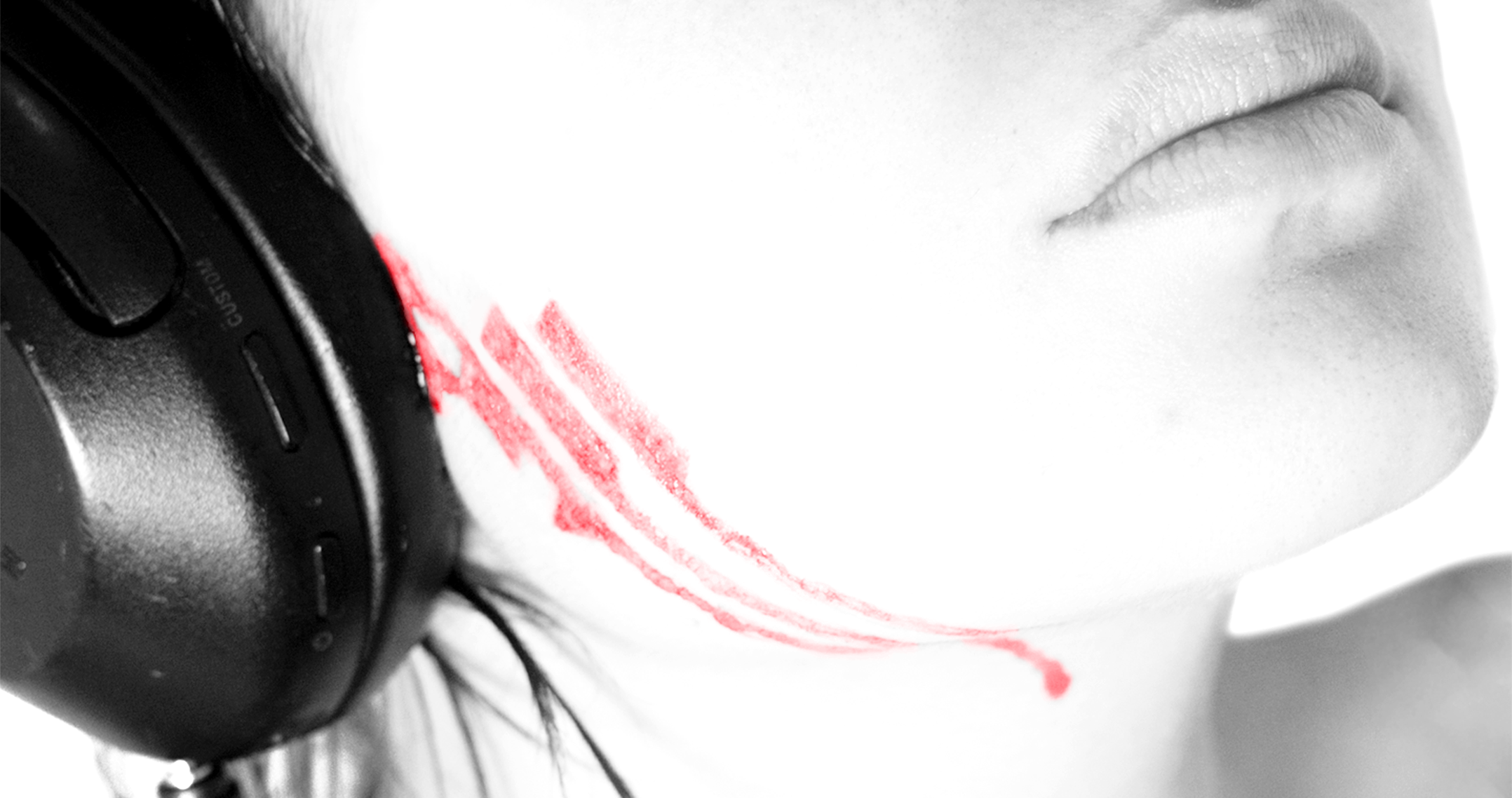 A close-up of a person's face with closed eyes, with red lipstick smudged on their chin, and wearing headphones.