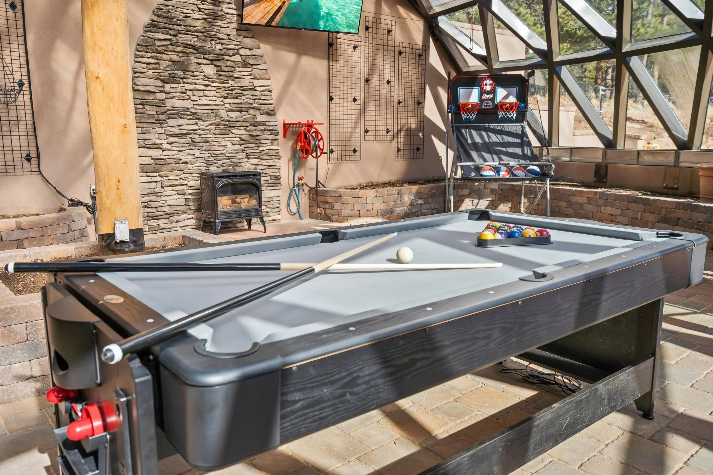 Indoor recreational area with pool table, a small fireplace, and basketball game.