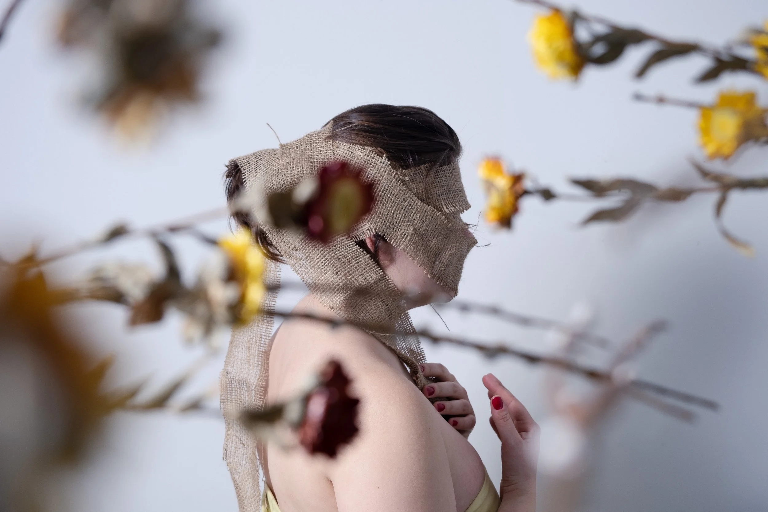 self portrait of young woman transforming with flowers and wraps as symbol of spring time